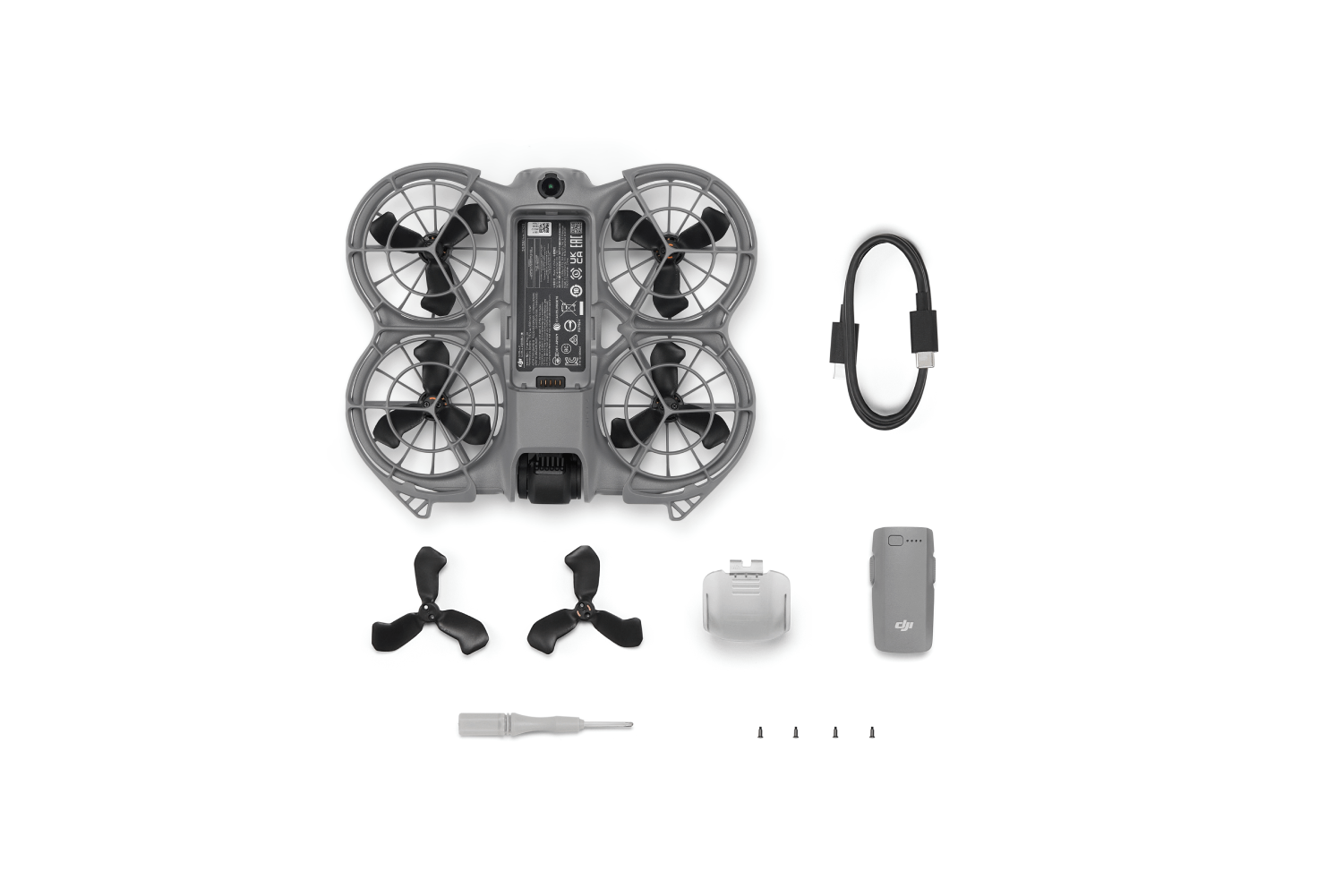 Dron con hélices, cargador, batería, destornillador y tornillos sobre fondo blanco. Dron gris, hélices y accesorios negros.