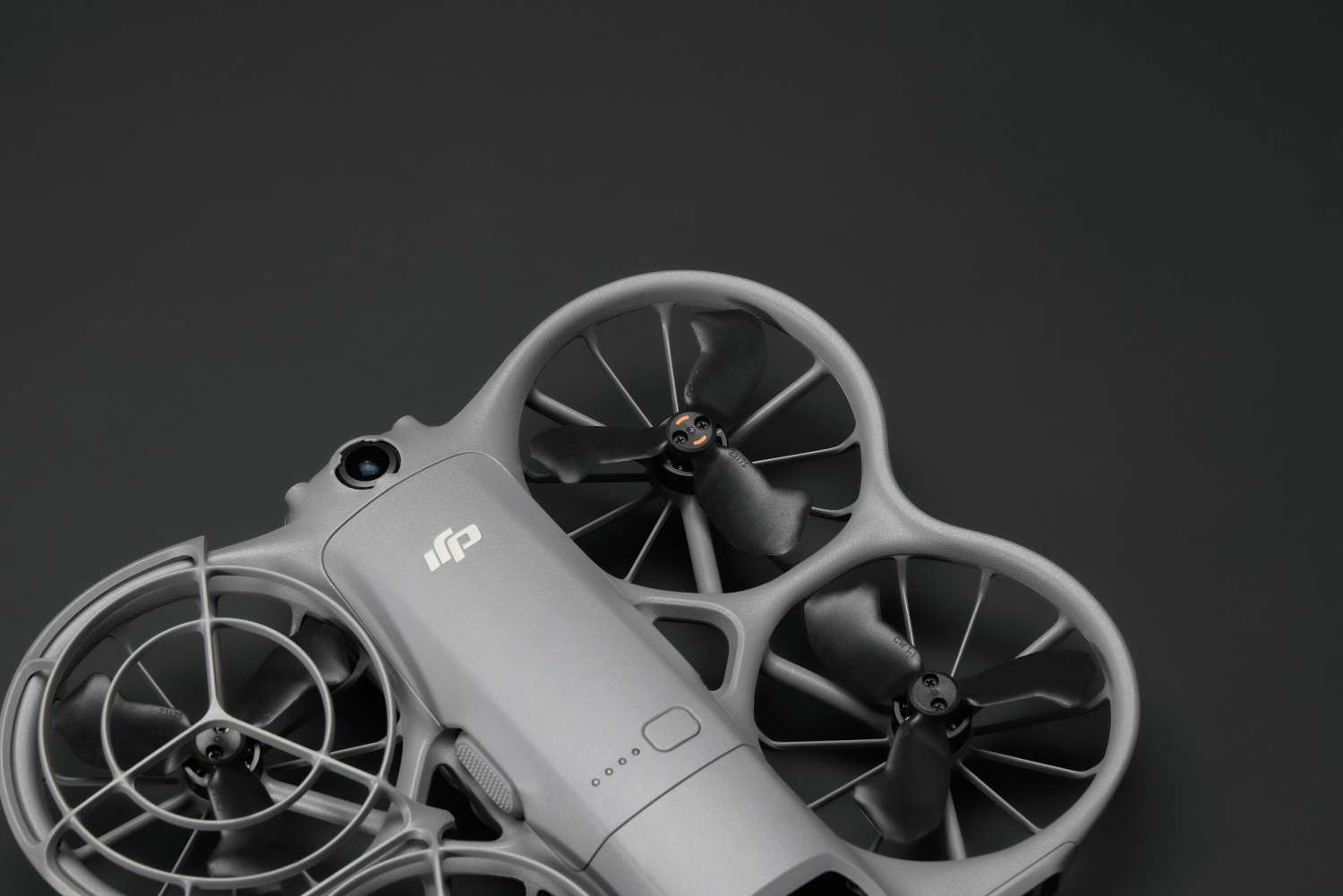Un dron gris con hélices negras sobre un fondo negro. El dron tiene una cámara y un logotipo DJI.