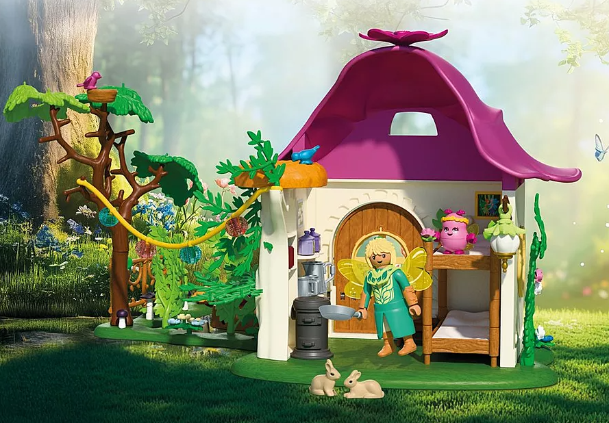 Ein Feenhaus mit einer Feenfigur, Hasen und einem Baum. Das Haus hat ein rosa Dach. Die Fee hält eine Pfanne.