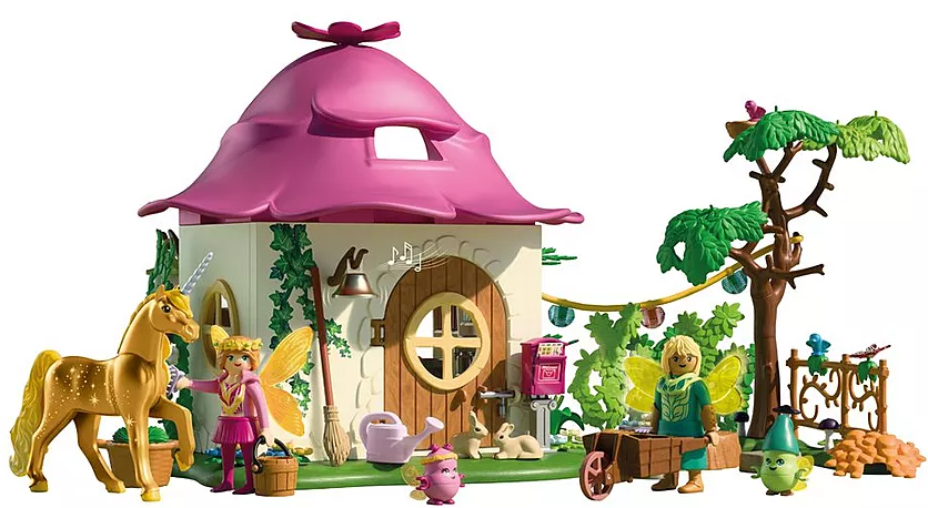 Ein Spielzeug-Feenhaus mit rosa Dach. Figuren sind eine Fee mit einem Einhorn, eine Fee, die einen Wagen schiebt, und andere Feenfiguren.