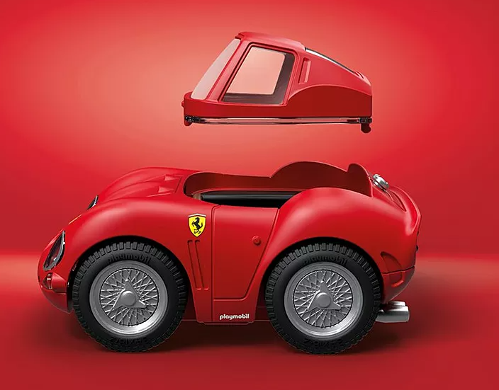 Roter Spielzeug-Ferrari mit abnehmbarem Dach. Merkmale sind silberne Räder, ein gelbes Ferrari-Emblem und ein roter Hintergrund.