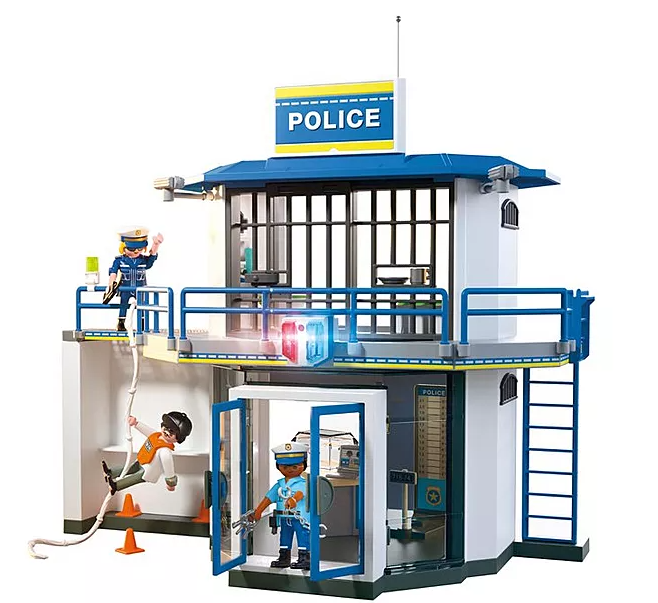 Ein Spielzeug-Polizeistation mit Figuren. Eine Frau winkt. Eine Person klettert an einem Seil. Ein Polizist steht im Inneren.