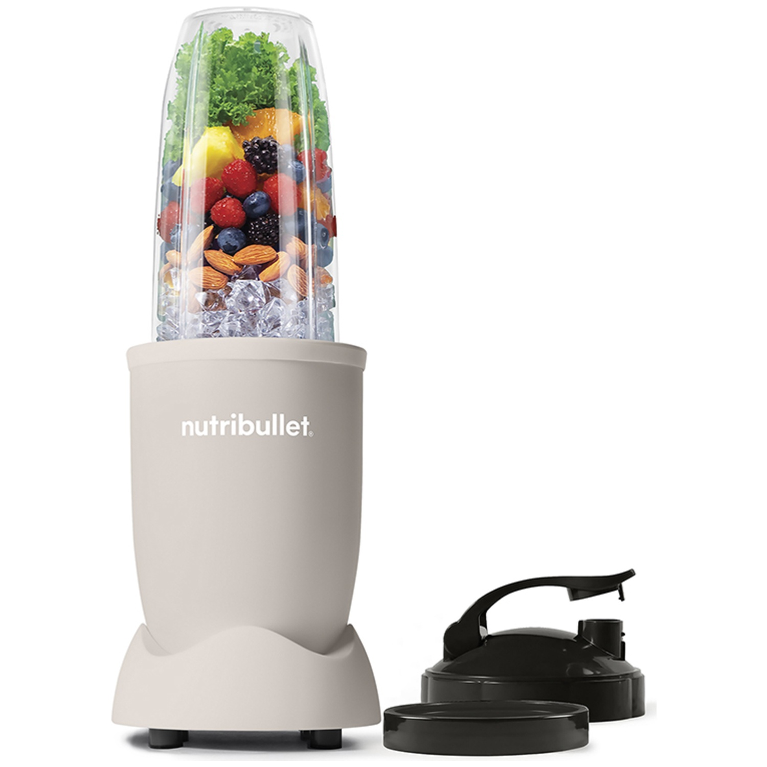 A beige Nutribullet blender filled with fruits, nuts, and ice. A black lid and cup are next to it. White background.