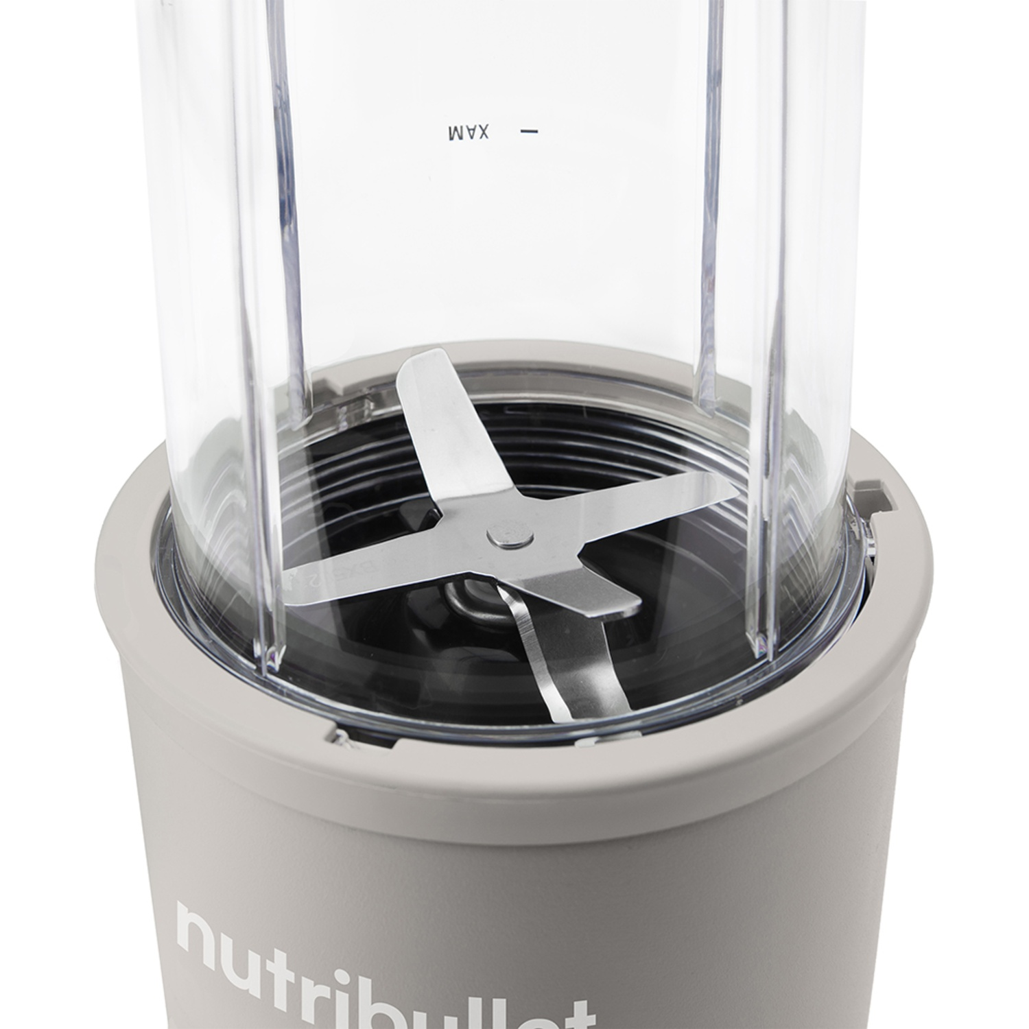 A close-up of a Nutribullet blender. The transparent container has a silver blade. The base is light gray.