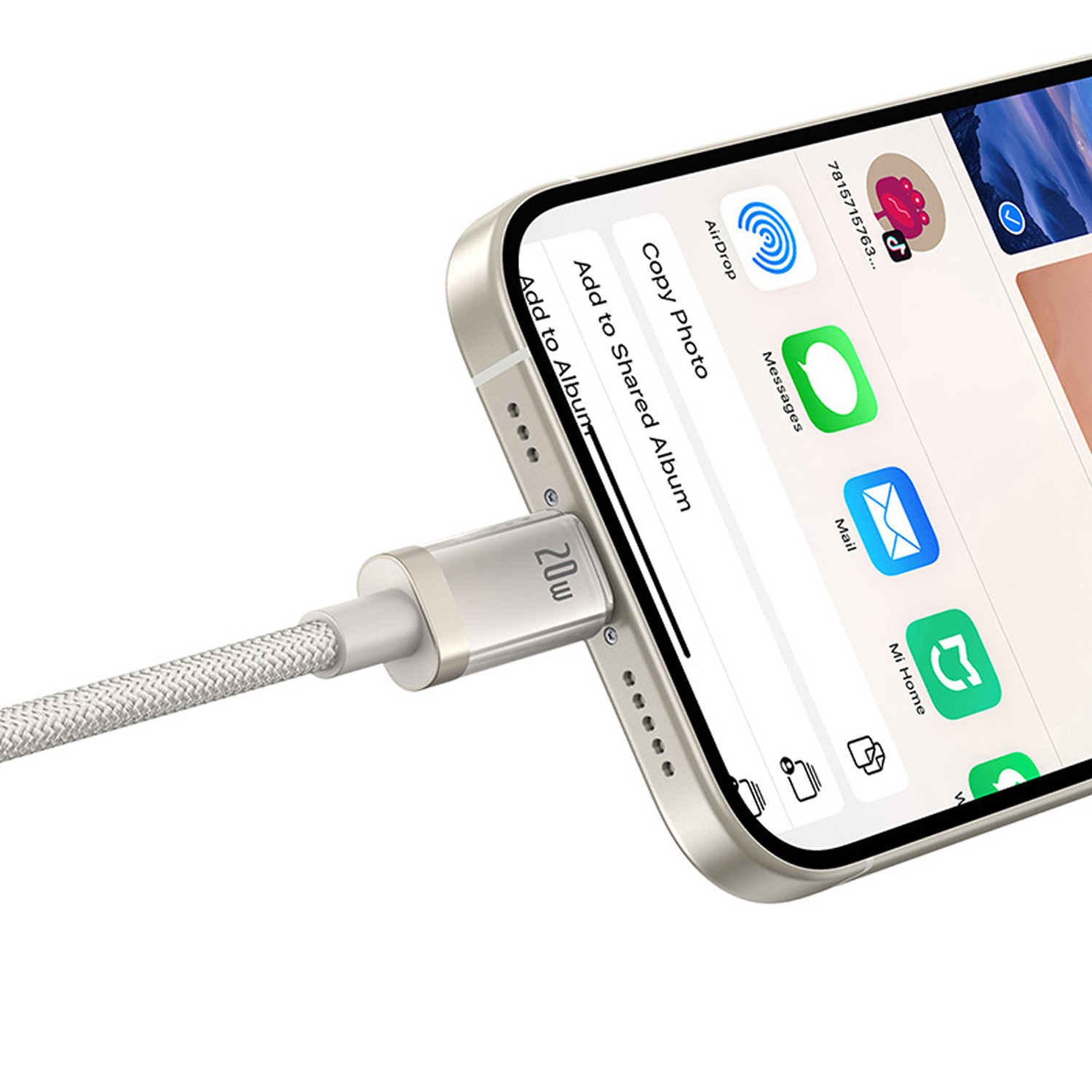 Un iPhone se está cargando con un cable plateado. La pantalla muestra iconos de aplicaciones. En el cargador pone '20w'.