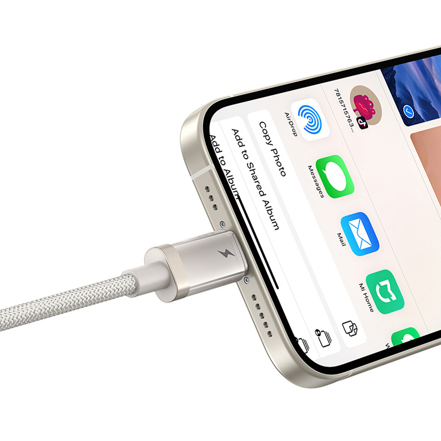 Un teléfono se está cargando con un cable plateado. La pantalla muestra iconos de aplicaciones como AirDrop, Messages y Mail.