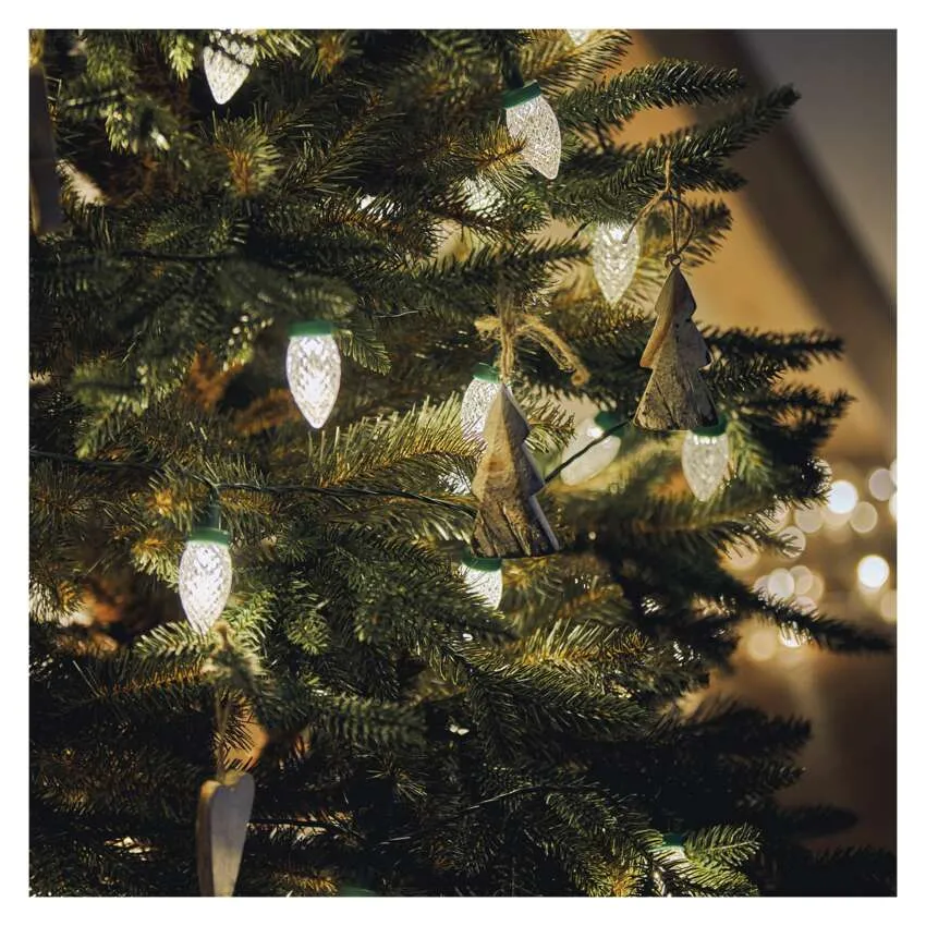 Egy karácsonyfát fehér lámpákkal és fa díszekkel díszítettek. A fa zöld, a háttér elmosódott bokeh fényekkel.