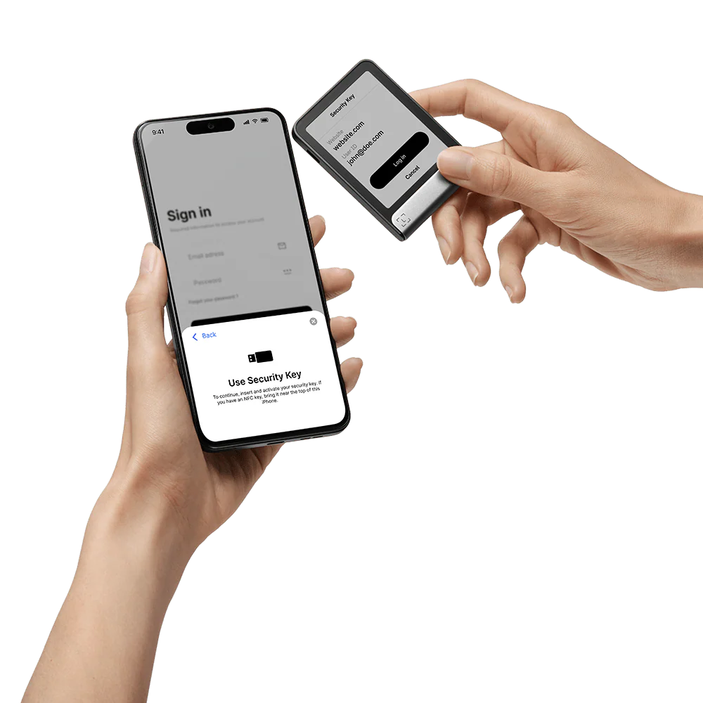 Hände halten Telefon und Sicherheitsschlüssel. Der Telefonbildschirm zeigt eine Anmeldeseite. Schlüssel hat eine Website und Benutzer-ID.