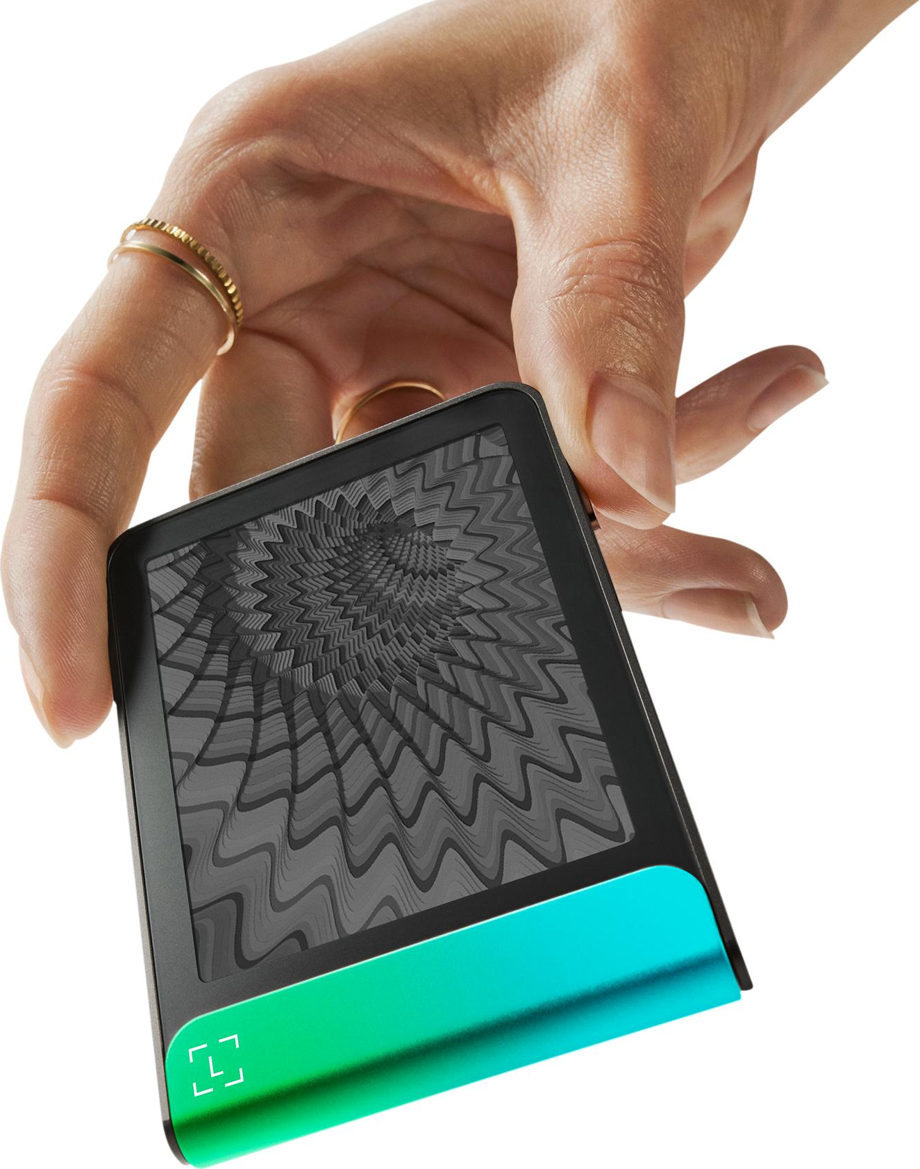 Mano che tiene un tablet nero con base verde-blu. Lo schermo mostra un motivo a onde grigie. Anelli adornano le dita.