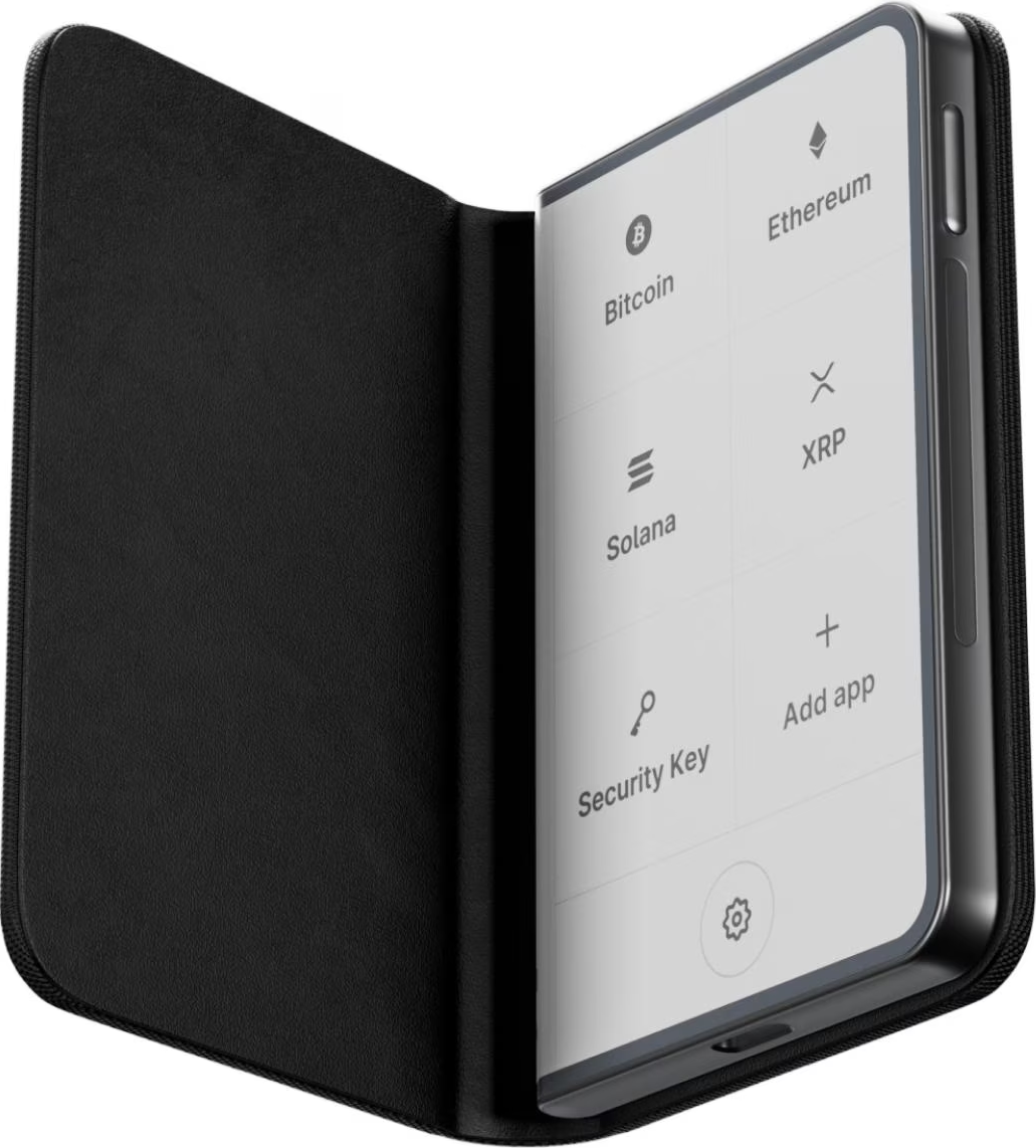 Ein schwarzes, brieftaschenähnliches Gerät zeigt einen Bildschirm mit Kryptowährungsoptionen: Bitcoin, Ethereum, Solana, XRP, Sicherheitsschlüssel und App hinzufügen.
