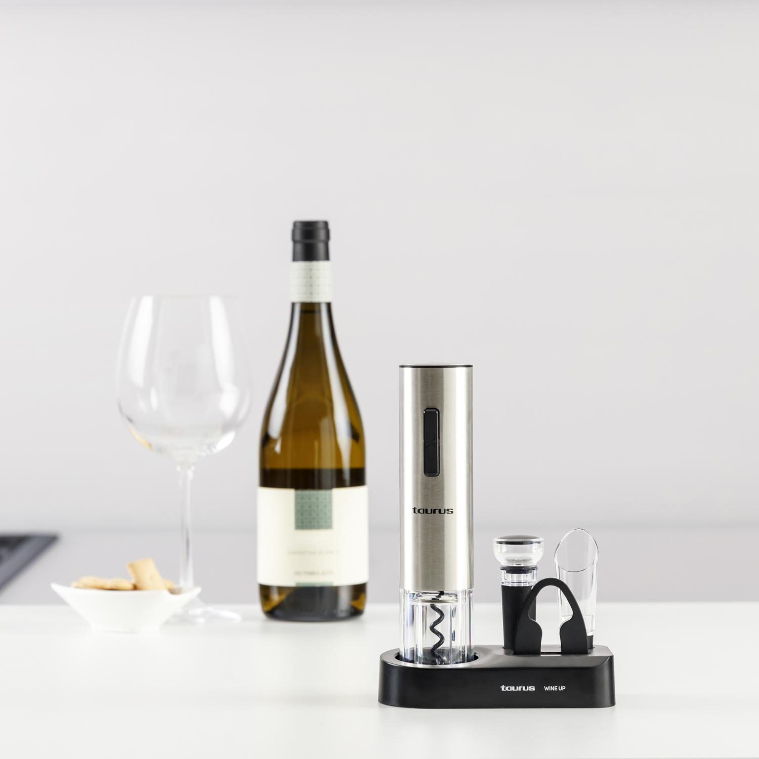 Butelka wina, kieliszek i akcesoria do wina na białej powierzchni. Akcesoria obejmują korkociąg i czarny stojak.