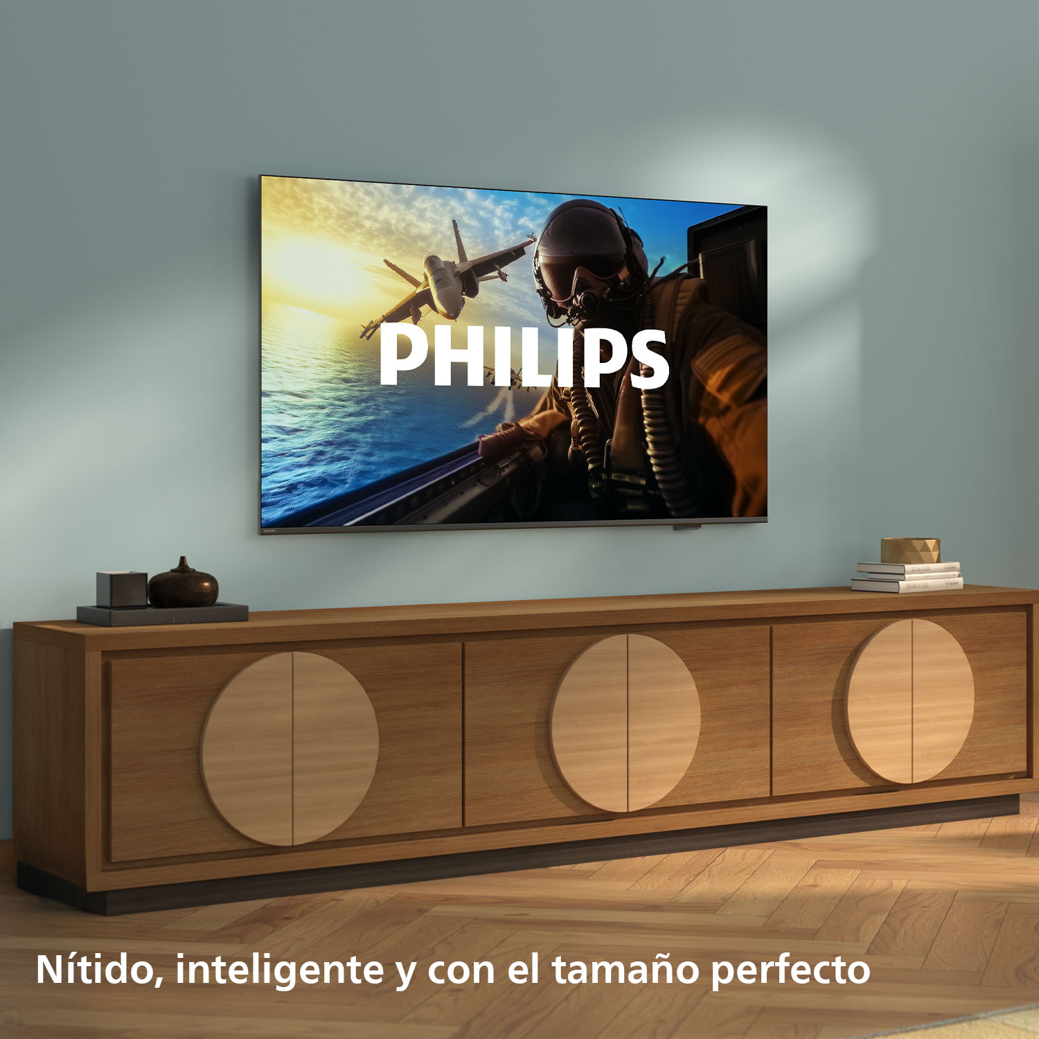 Un televisor muestra un avión a reacción volando sobre el agua. La palabra 'PHILIPS' está en la pantalla. Debajo hay un mueble de madera.