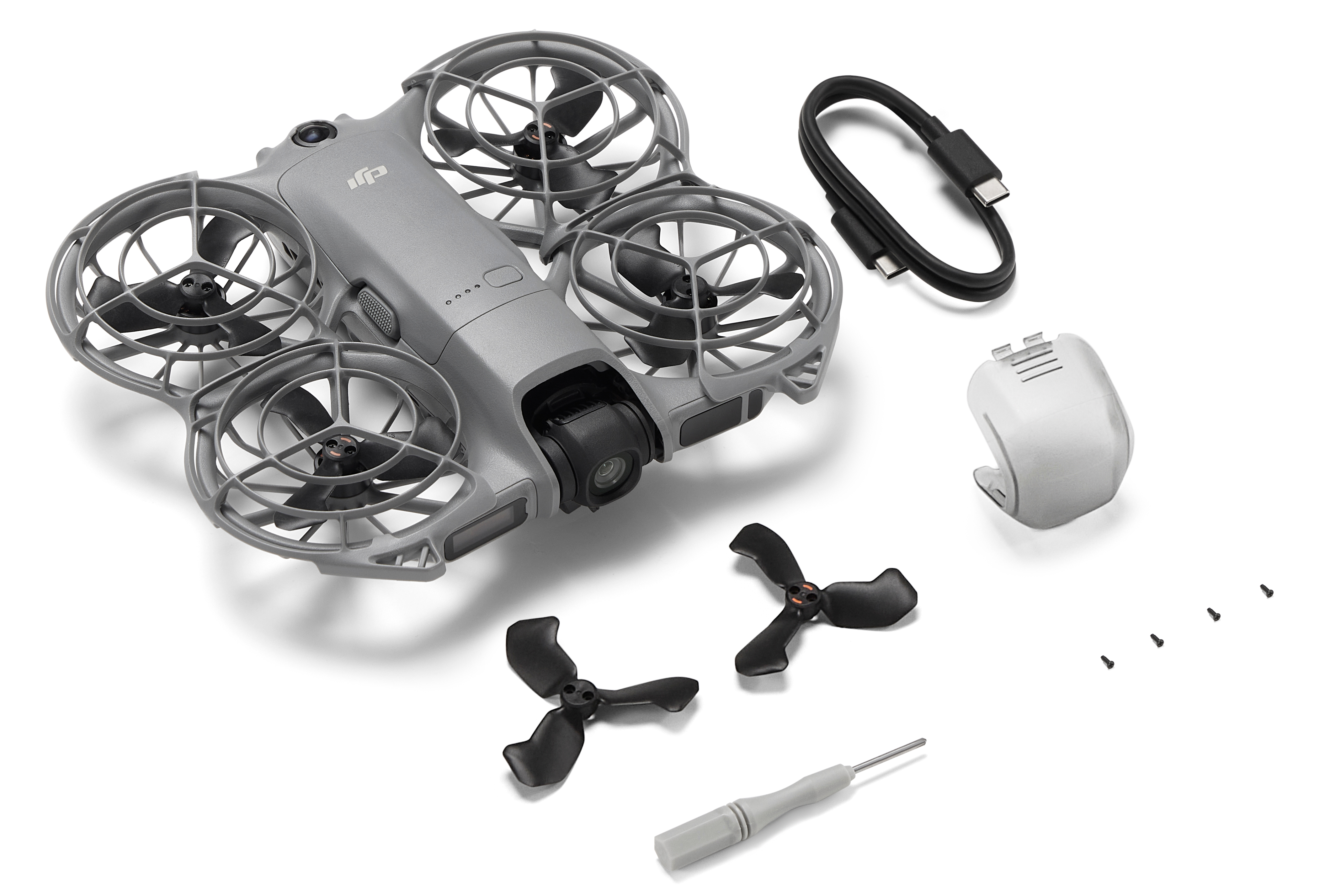 Szary dron ze śmigłami, czarnym kablem, rekwizytami, śrubokrętem i częściami zamiennymi na białym tle.