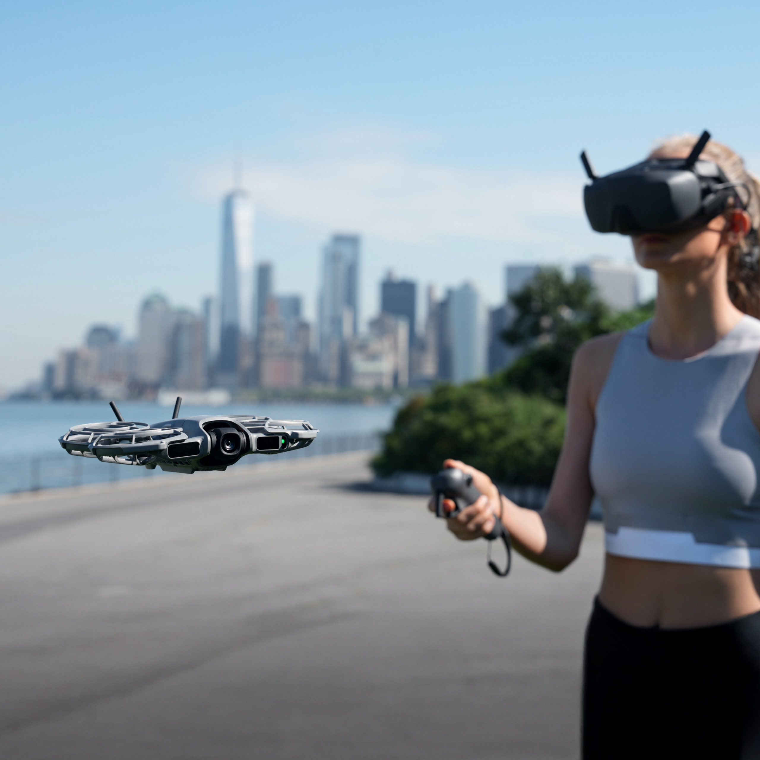 Eine Frau mit VR-Brille steuert eine Drohne. Im Hintergrund ist eine Skyline zu sehen. Die Drohne befindet sich in der Luft.