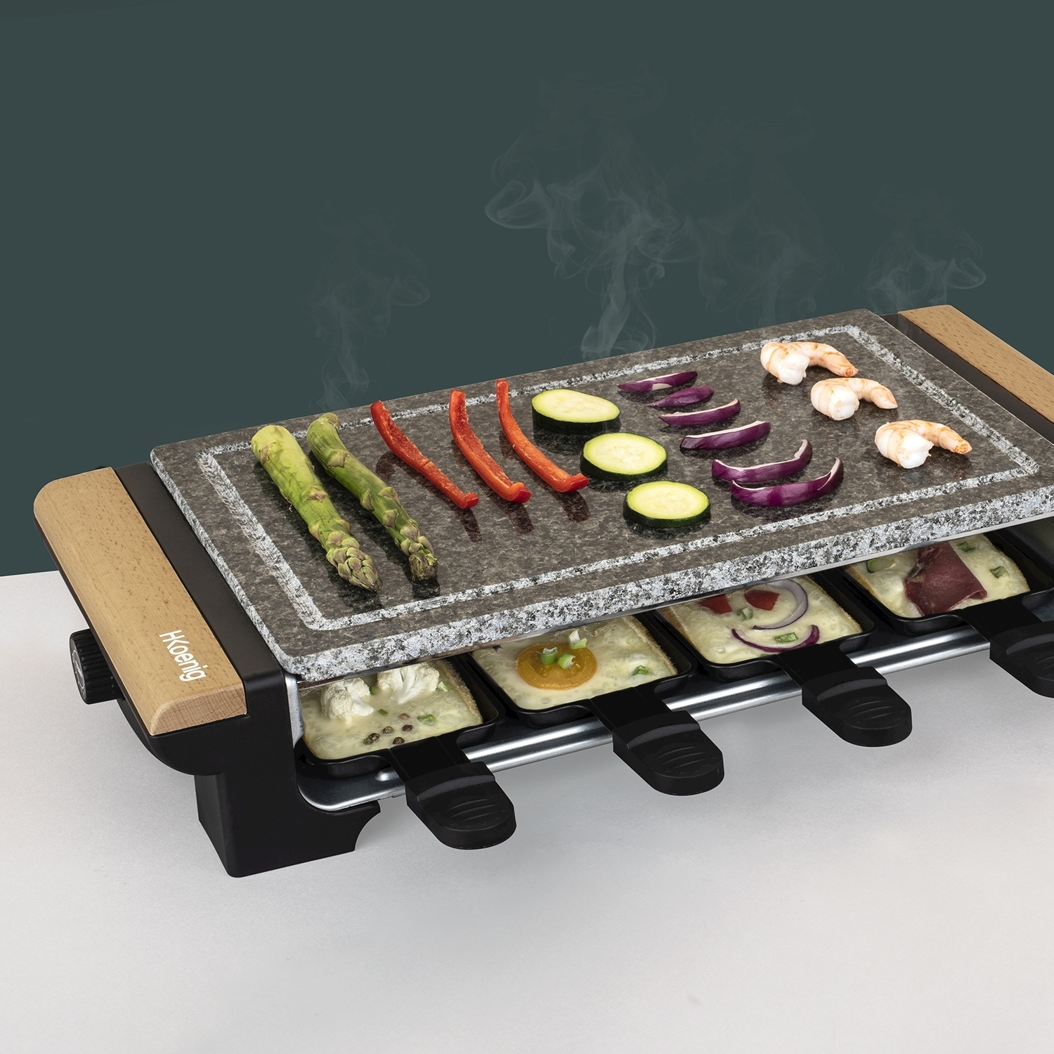 Griglia per raclette con verdure e gamberi sopra. Formaggio nei vassoi sottostanti. Vapore che sale. Legno e metallo nero.