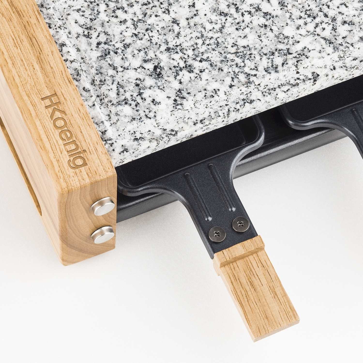 Primo piano di una griglia per raclette. Ha una superficie di cottura in granito, manici in legno e una base nera. Il marchio è visibile.