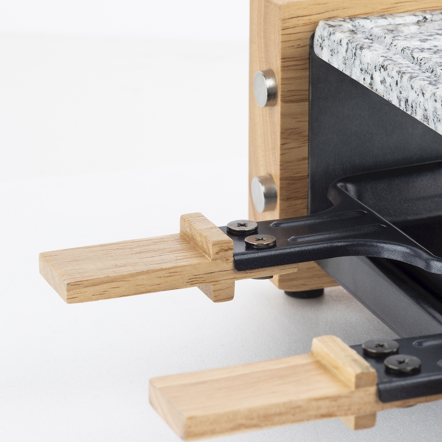 Primo piano di una griglia per raclette. Supporti in legno con base in metallo nero. Piano in granito e telaio in legno. Viti e cilindri metallici visibili.