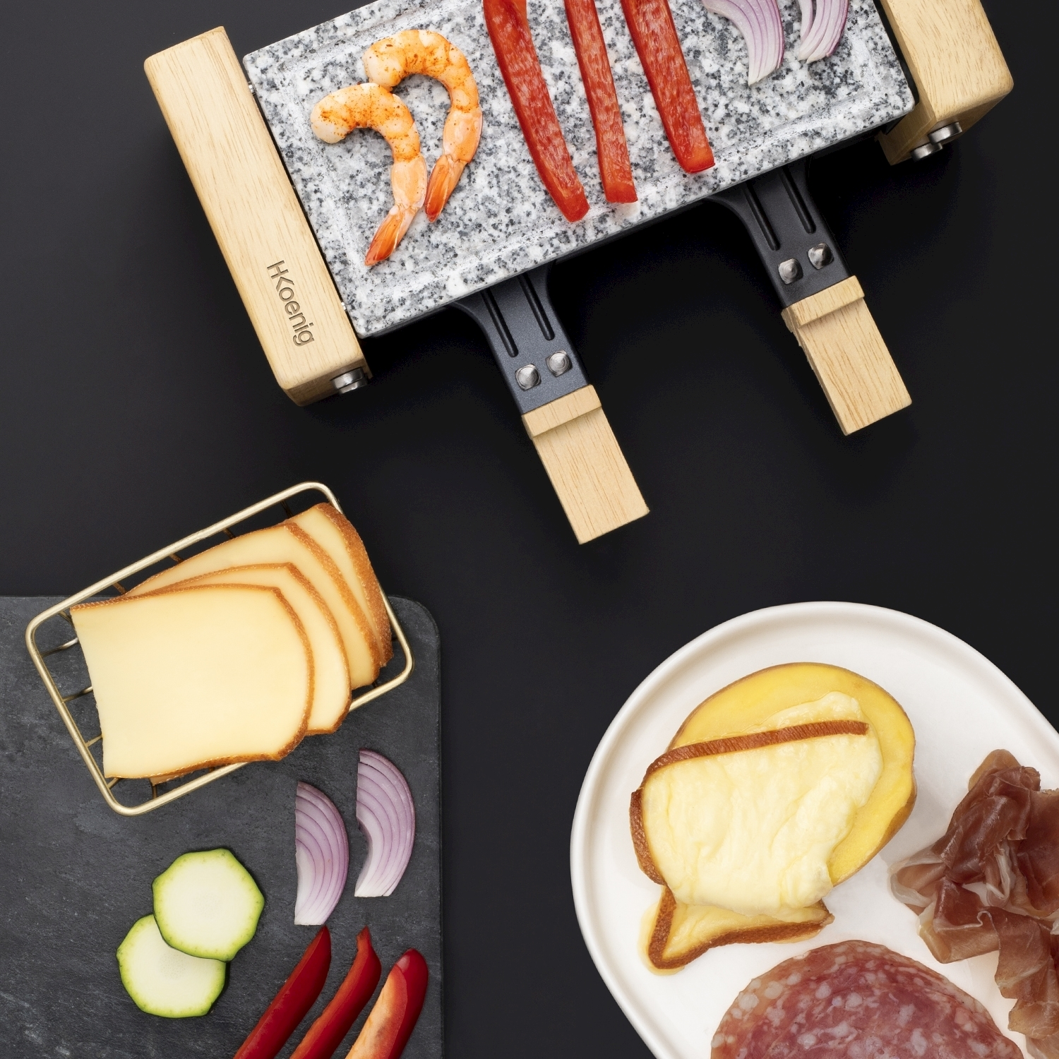 Griglia per raclette con gamberi, peperoni e cipolle. Formaggio, salame e prosciutto su piatto bianco e nero.