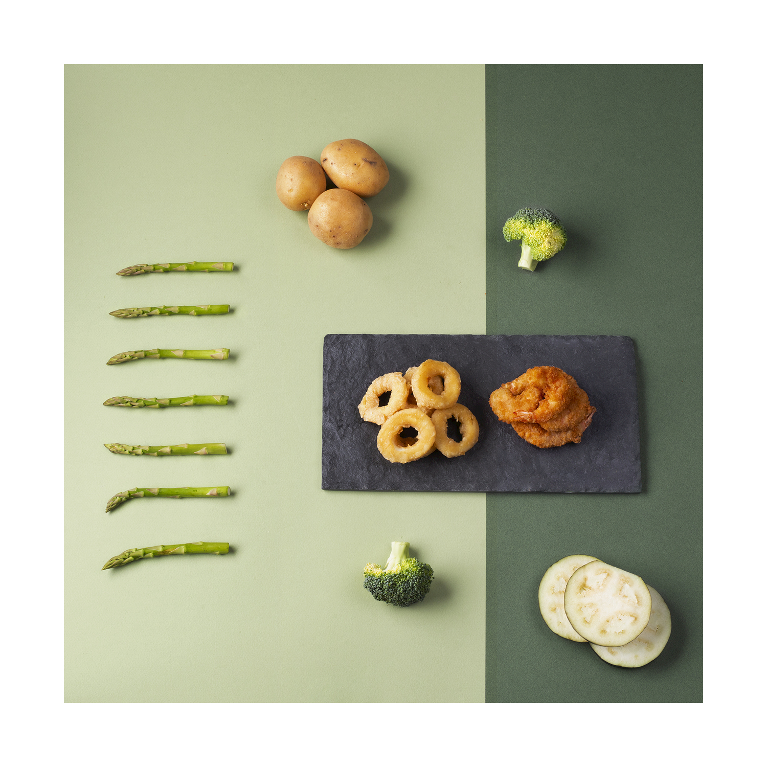 Vista dall'alto del cibo. Asparagi, patate, broccoli, anelli di cipolla e gamberi fritti e fette di zucchine sono disposti su uno sfondo bicolore.