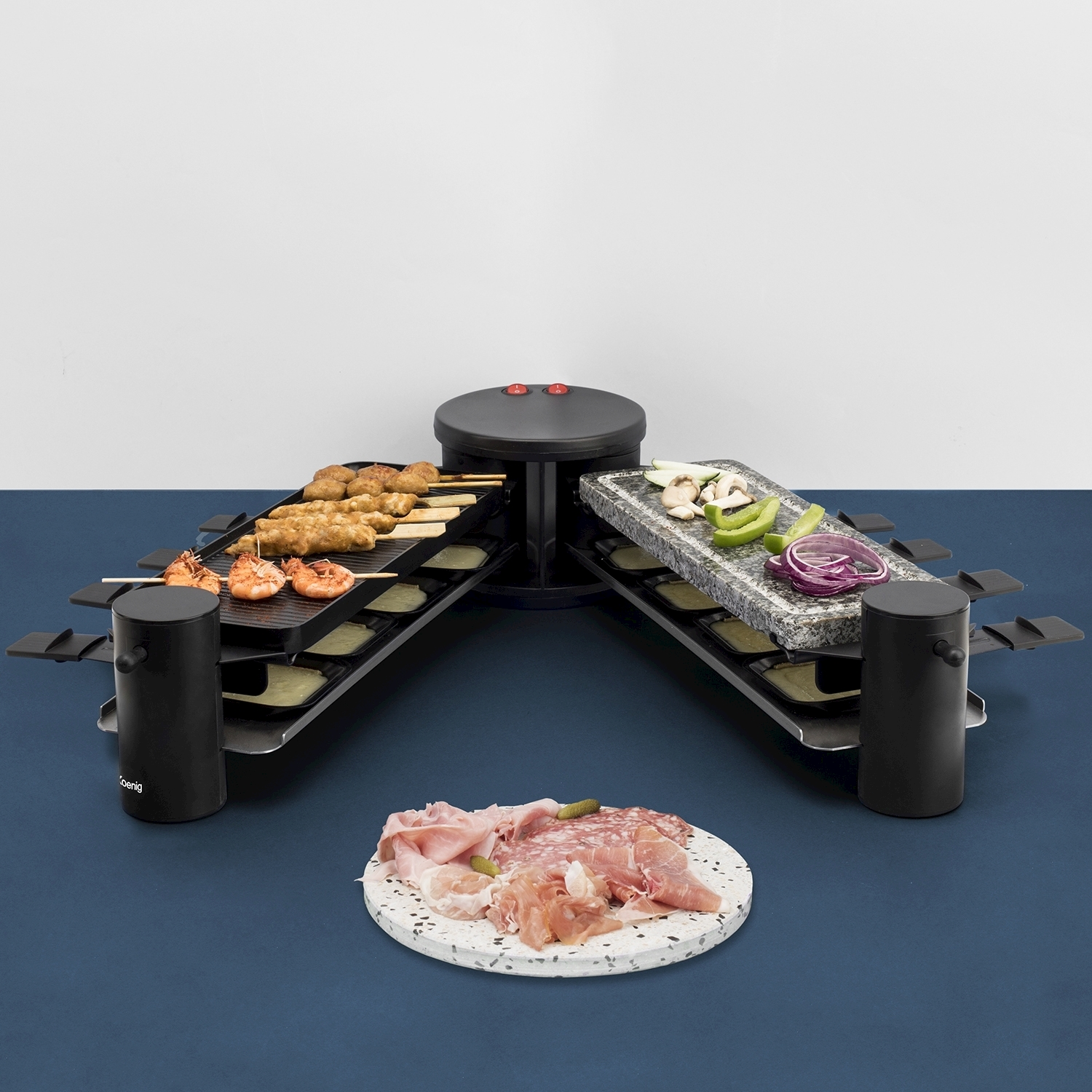 Grill per raclette con carne, gamberi, verdure su una superficie blu. Carne affettata su un piatto rotondo. Sfondo bianco.