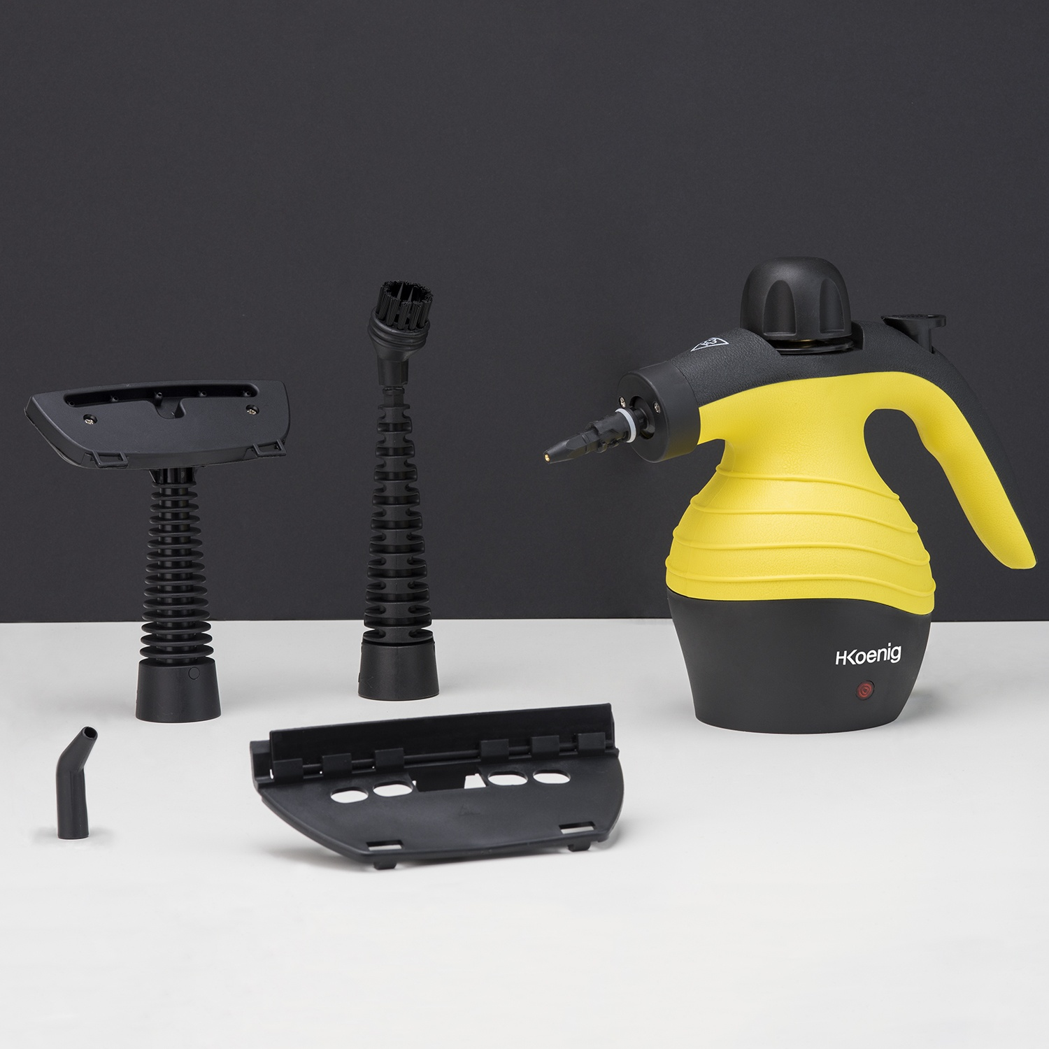 Un pulitore a vapore giallo e nero con accessori su una superficie bianca e sfondo nero. Il marchio è HKoenig.