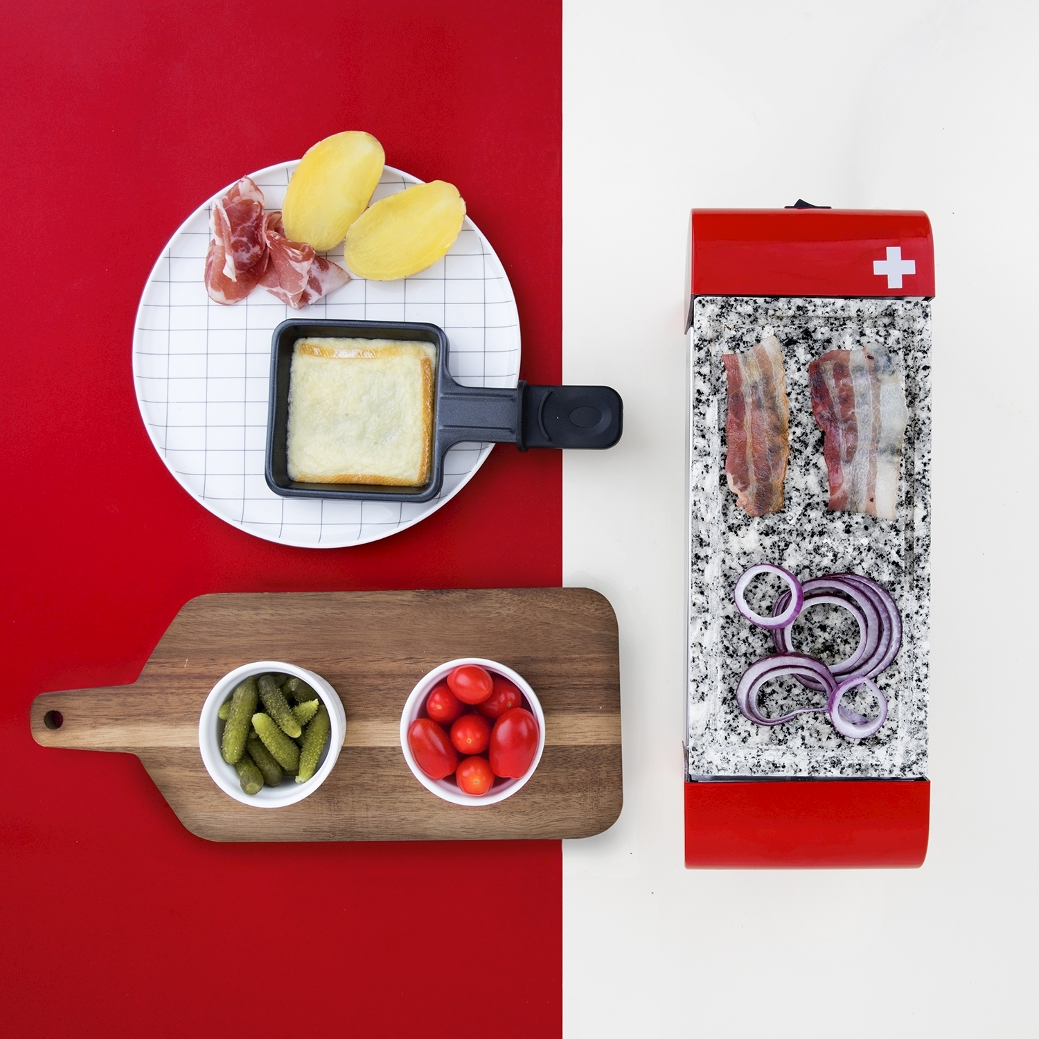 Ingredienti per la raclette: formaggio, patate, prosciutto, pancetta, cipolla rossa, pomodori e sottaceti. Presentato su sfondi rossi e bianchi.