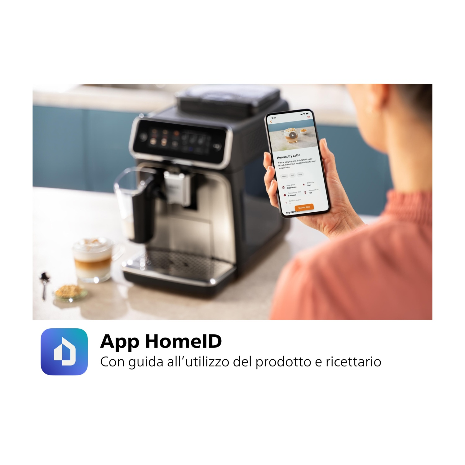 Una donna tiene un telefono che mostra una ricetta di caffè vicino a una macchina da caffè e una tazza di caffè. Logo App HomeID visibile.