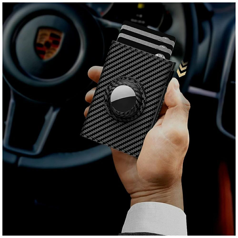 Dłoń trzymająca portfel z włókna węglowego z kartami. Kierownica Porsche w tle.