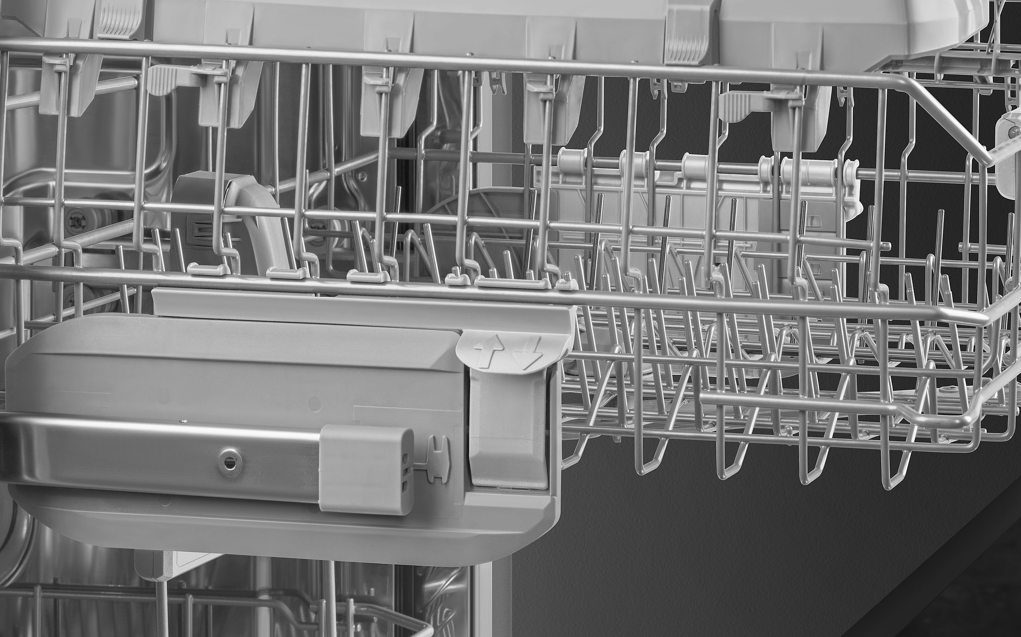 Im Inneren eines Geschirrspülers sind die grauen Metallgestelle, Fächer und Sprüharme zu sehen. Das Design ist industriell und funktional.