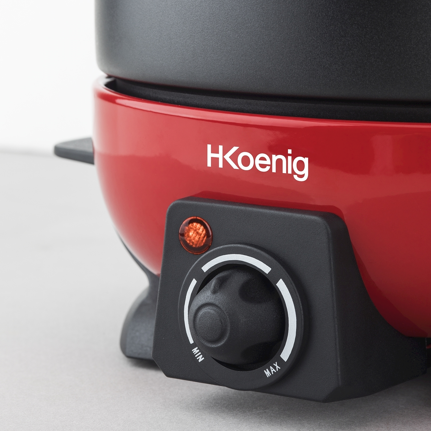 Primo piano di un elettrodomestico rosso e nero, con un quadrante con scritto 'MIN' e 'MAX'. Visibile il marchio 'H Koenig'.