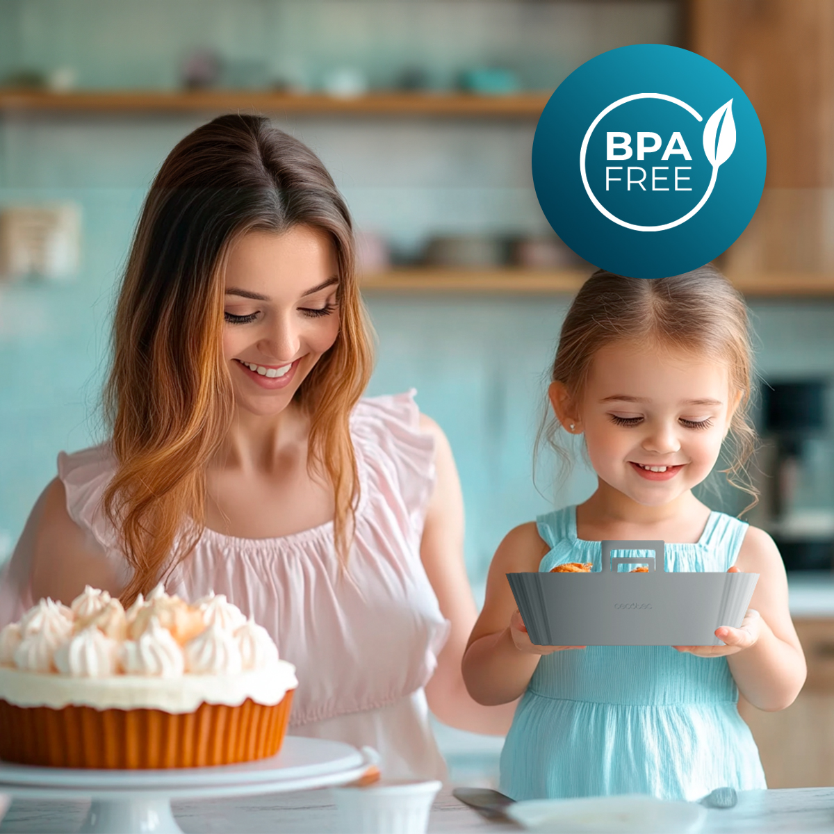 Una mujer y una niña sonríen cerca de un pastel. La niña sostiene una bandeja gris con comida. Un logo BPA free está detrás.