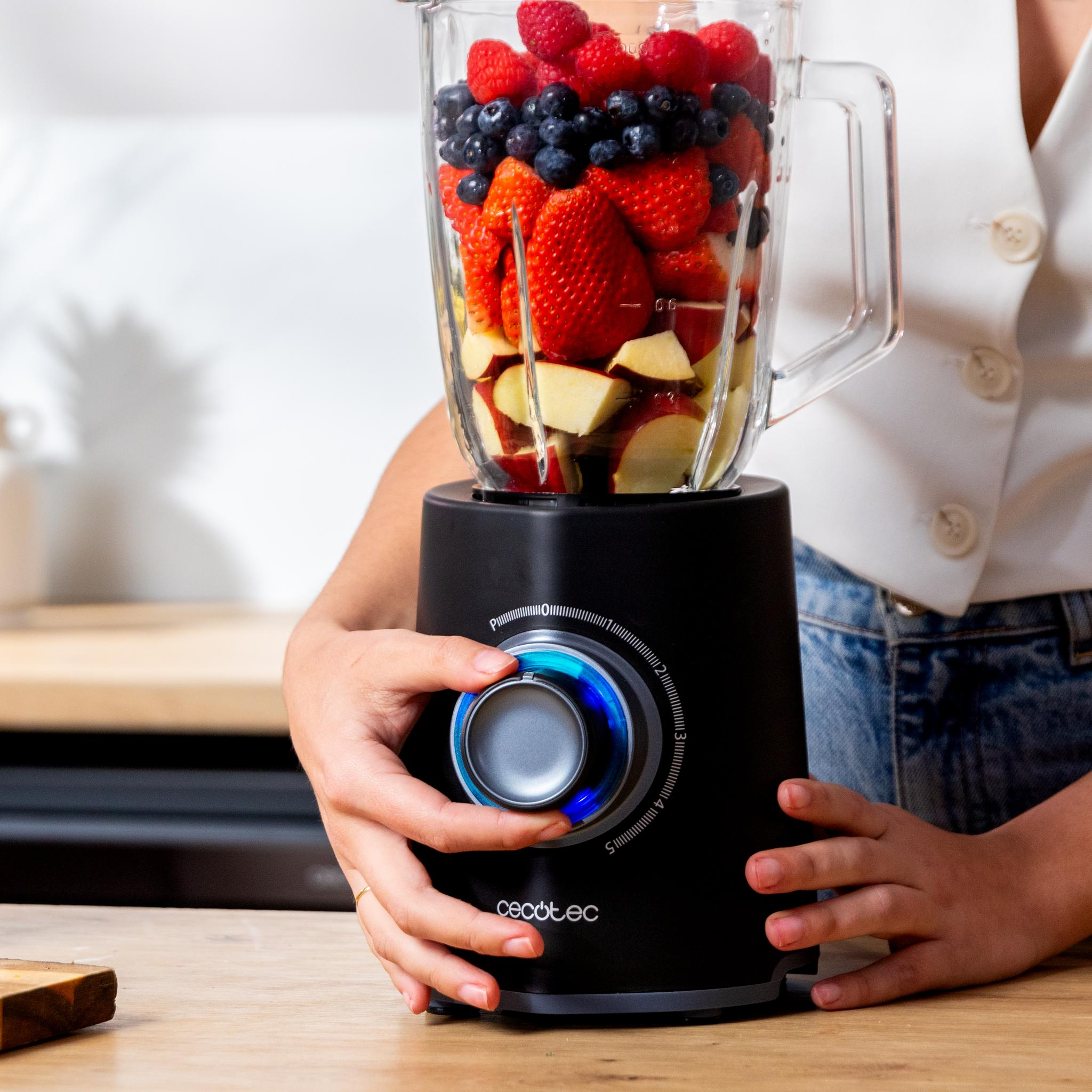 Se opera una licuadora llena de frutas. Se ven fresas, arándanos y manzanas.