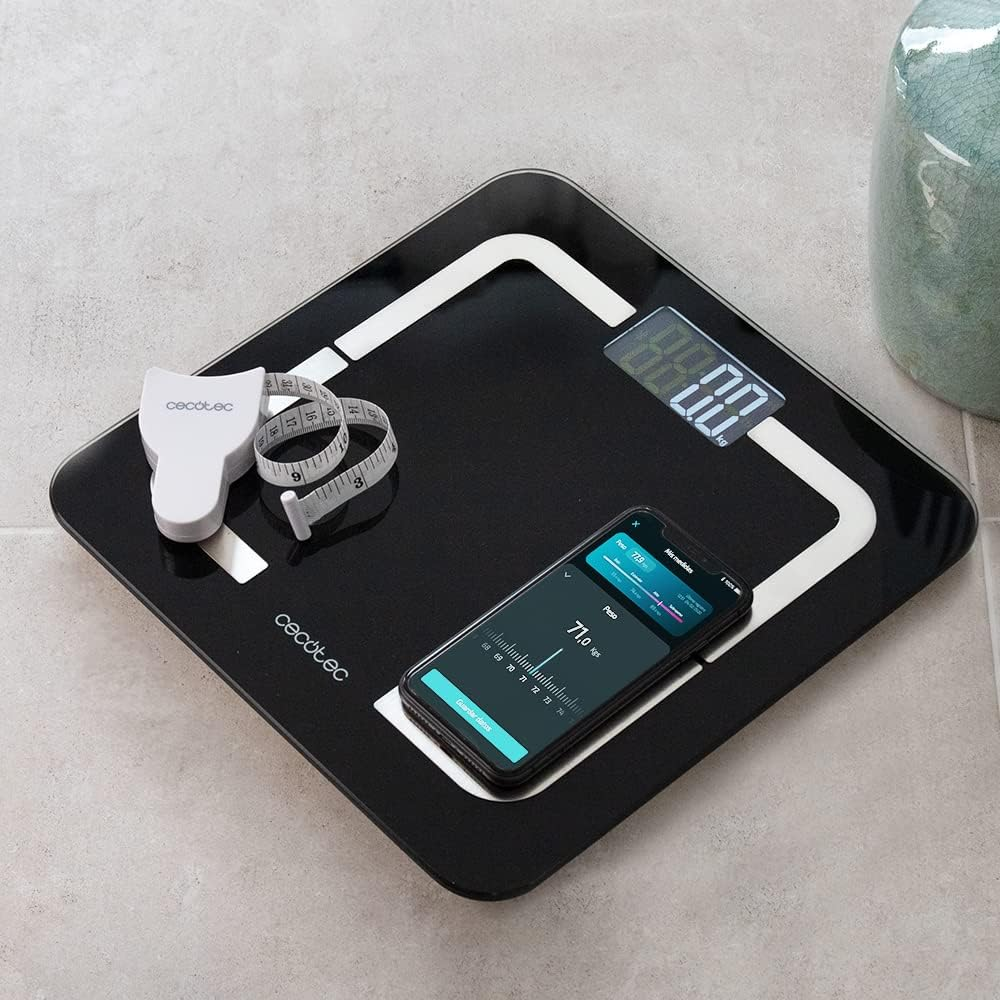 Una báscula digital negra muestra 88,0 kg. Un teléfono inteligente muestra 71,0 kg. También hay una cinta métrica blanca y un jarrón.