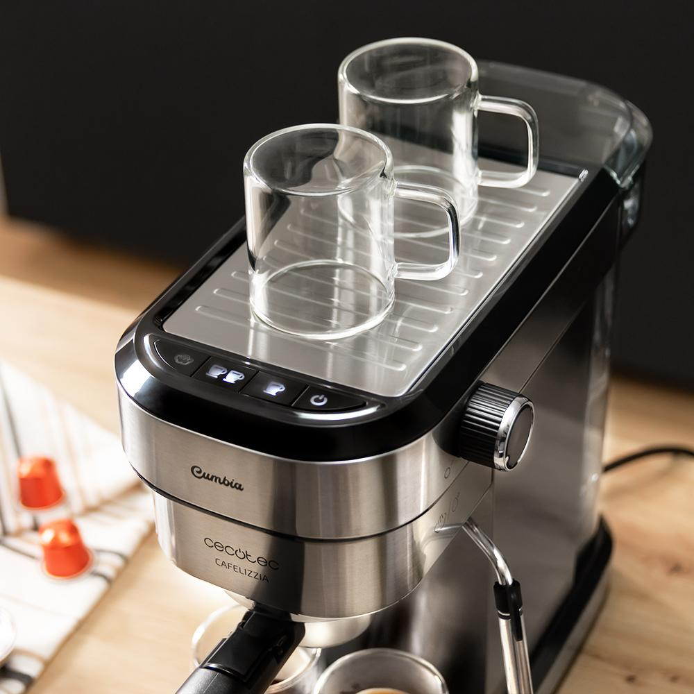 Primer plano de una cafetera con dos tazas de vidrio encima. La máquina es plateada y negra, con una superficie de madera debajo.