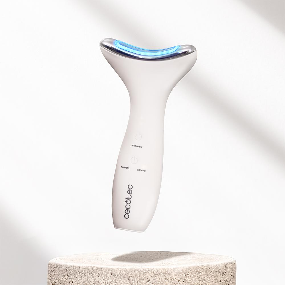 Un dispositivo facial blanco con luz azul se encuentra sobre un pedestal de piedra. Tiene botones para iluminar, tensar y calmar. La marca es Cecotec.