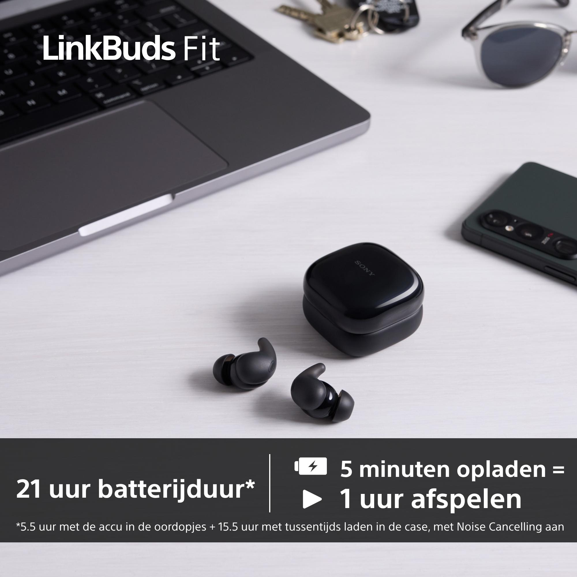 Zwarte Sony LinkBuds Fit oortelefoons, hoesje en telefoon op een wit oppervlak met laptop, zonnebril en sleutels.
