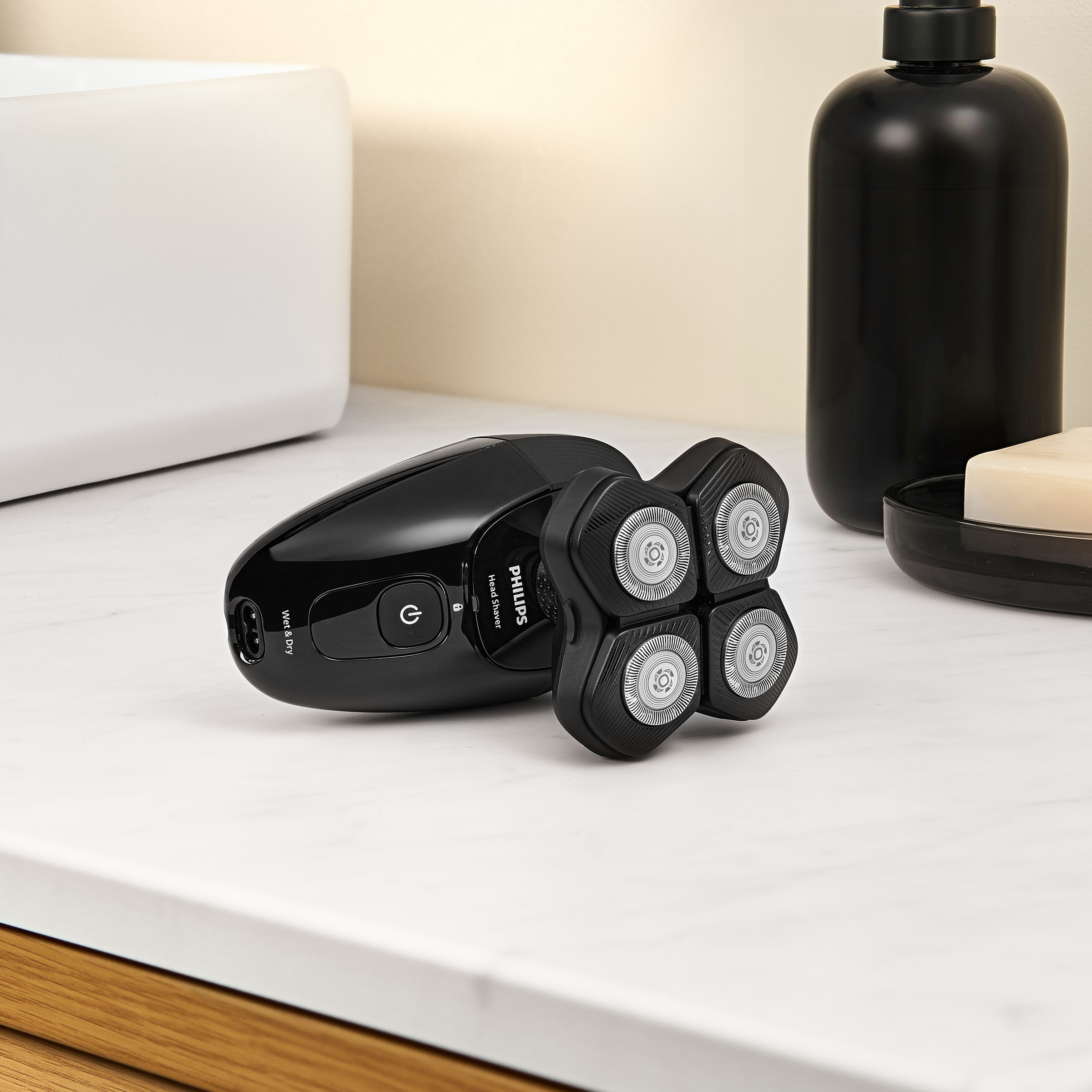 Czarna golarka Philips na blacie. Mydło i czarny dozownik w tle.