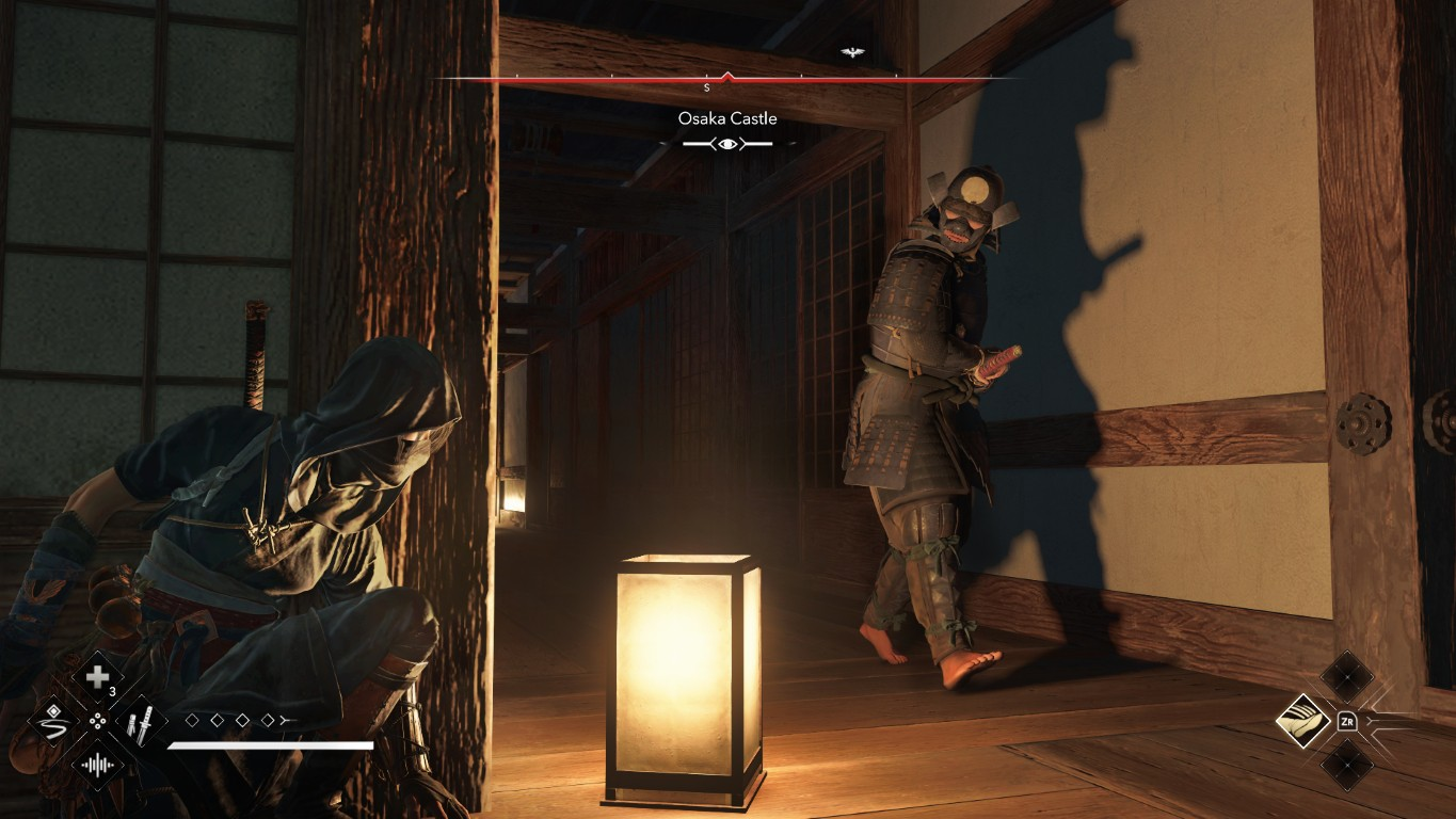 Ninja kuca w drewnianym korytarzu, naprzeciw samuraja. Podświetlana latarnia stoi na pierwszym planie. Scena to Zamek Osaka.