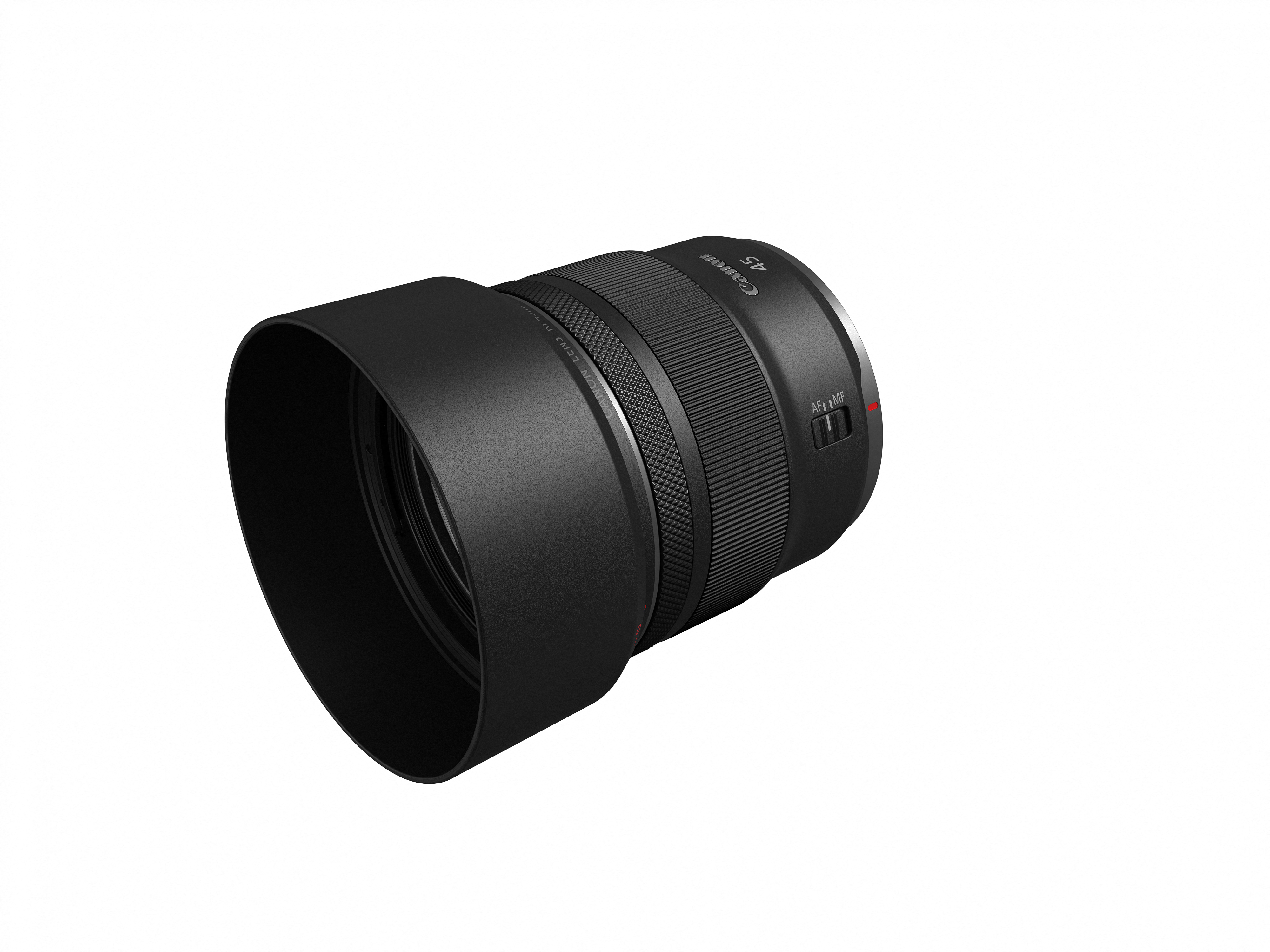 Ein schwarzes Canon RF 45mm Objektiv ist auf einer weißen Oberfläche angewinkelt. Das Objektiv hat eine Gegenlichtblende.