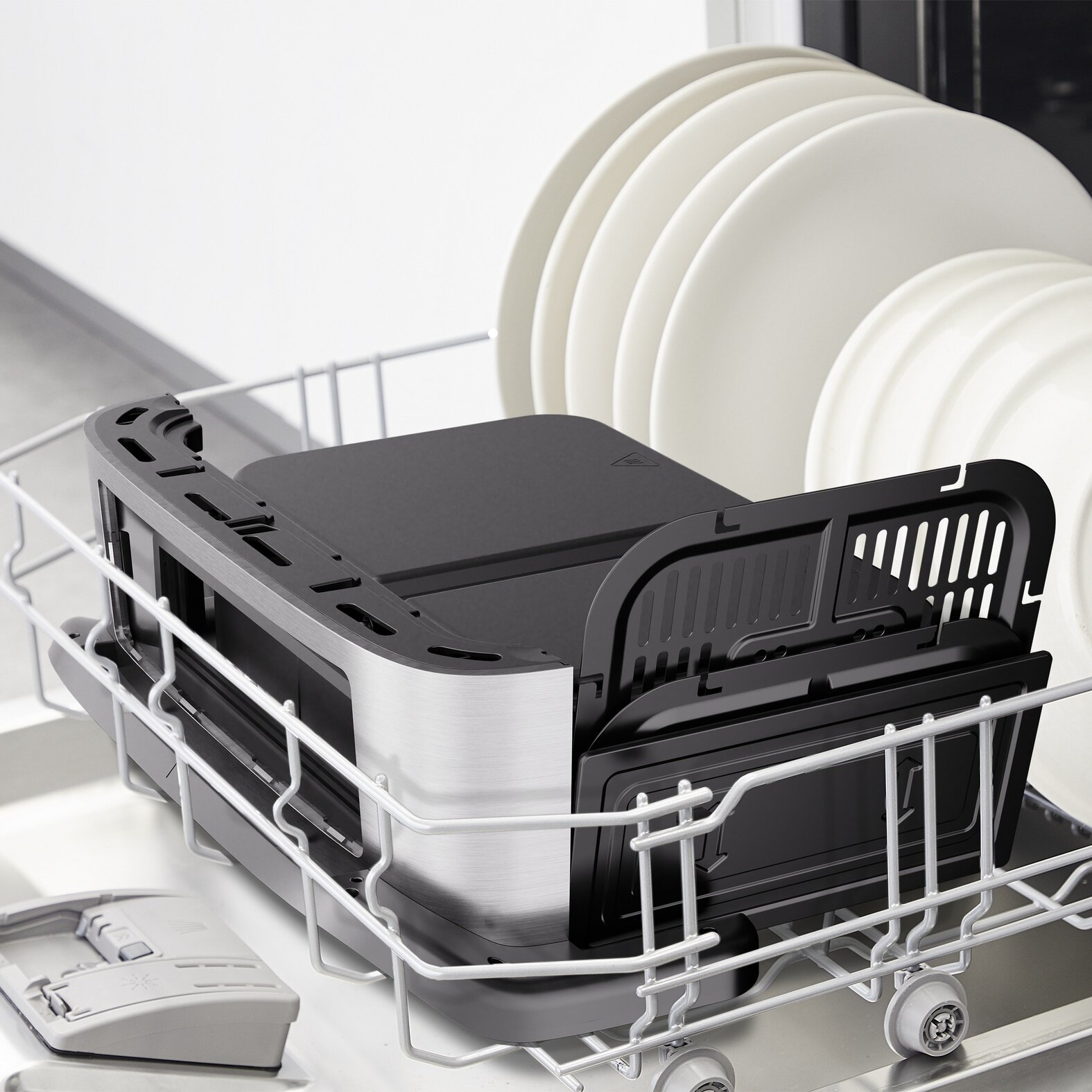 Zmywarka z czarnym i srebrnym urządzeniem w środku. Białe talerze w tle. Scena jest dobrze oświetlona.