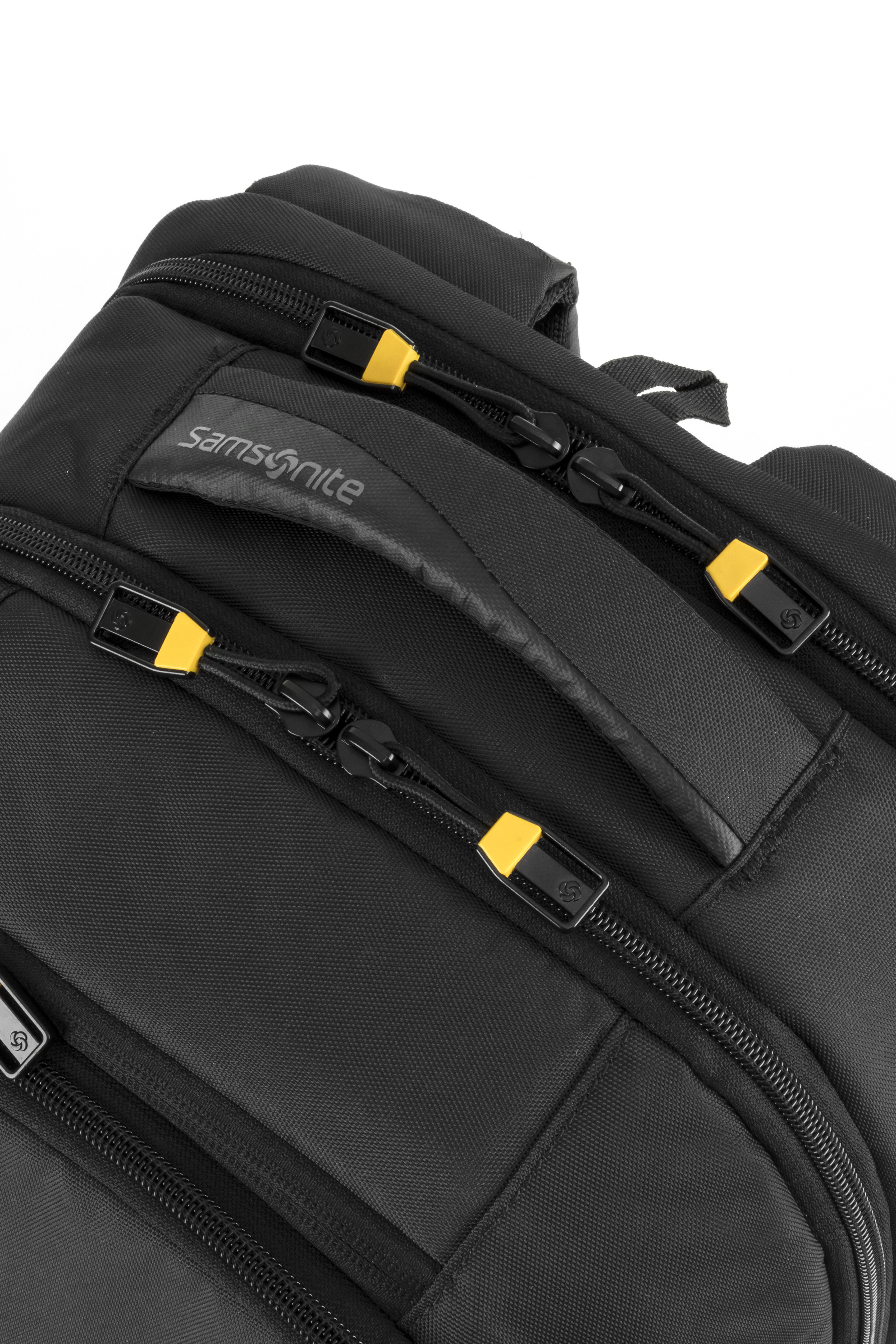 Siyah bir Samsonite sırt çantasının yakın çekimi. Sarı detaylı fermuarlar ve bir tutamak görülüyor.