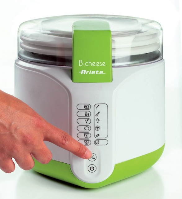 Biało-zielony serowar z ręką naciskającą przycisk 'OK'. Ma przezroczystą pokrywę i markę 'Ariete'.