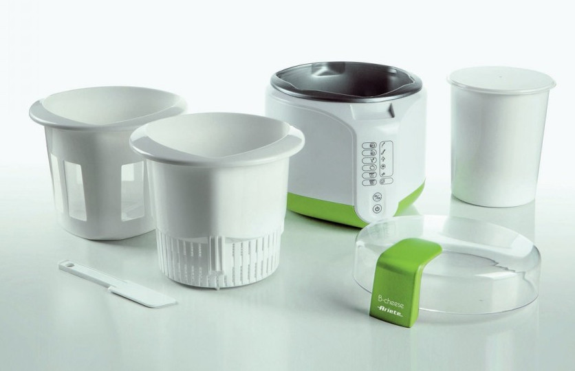 Biało-zielony ekspres do sera z komponentami: pojemniki, pokrywki i szpatułka. Nazwa marki jest widoczna na pokrywie.