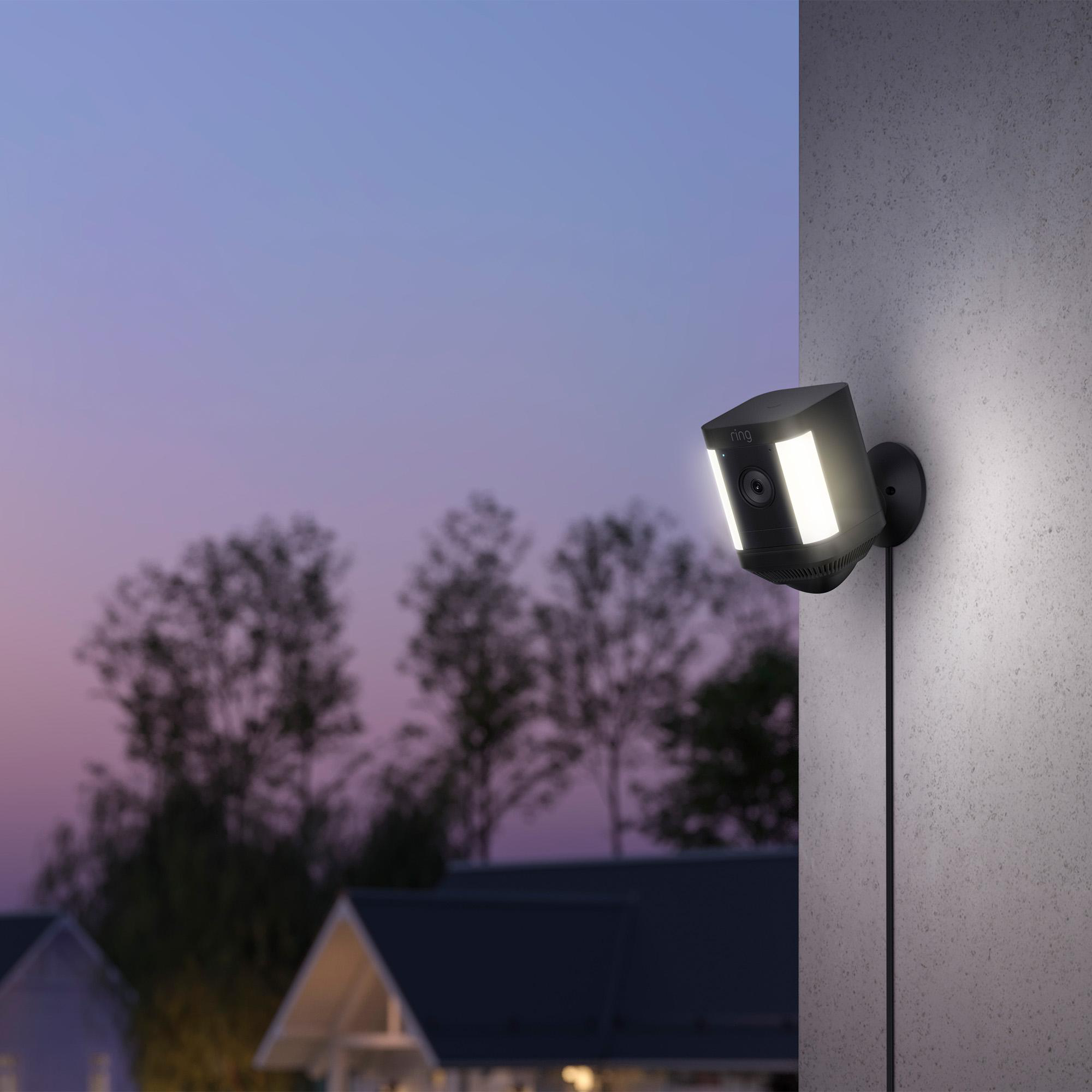 Eine schwarze Ring-Sicherheitsleuchte ist an einer grauen Wand montiert und in der Abenddämmerung beleuchtet.