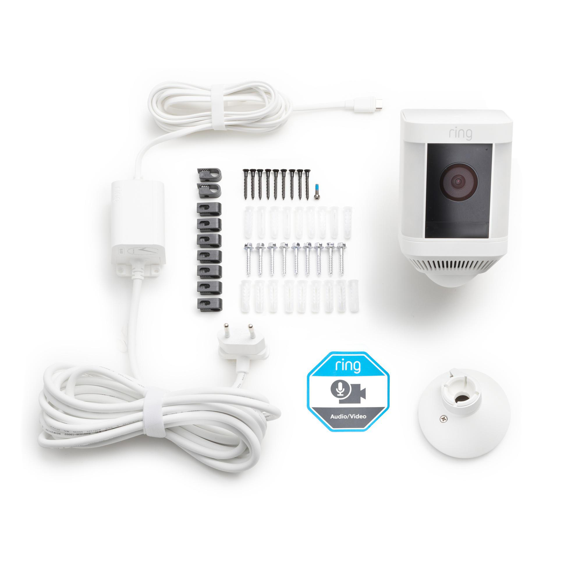 Weißes Ring-Sicherheitskamera-Kit mit verschiedenen Komponenten, darunter Schrauben, Kabel und ein Netzteil, auf weißem Hintergrund.