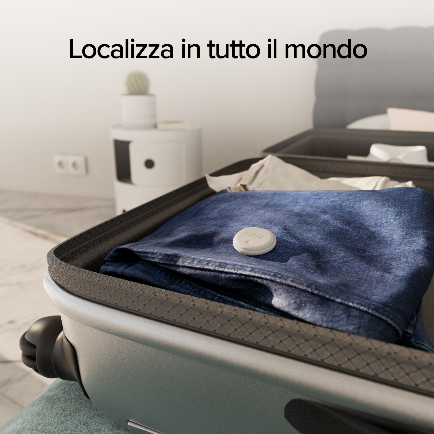 Valigia aperta con jeans blu e un dispositivo di localizzazione bianco. Testo: 'Localizza in tutto il mondo'.