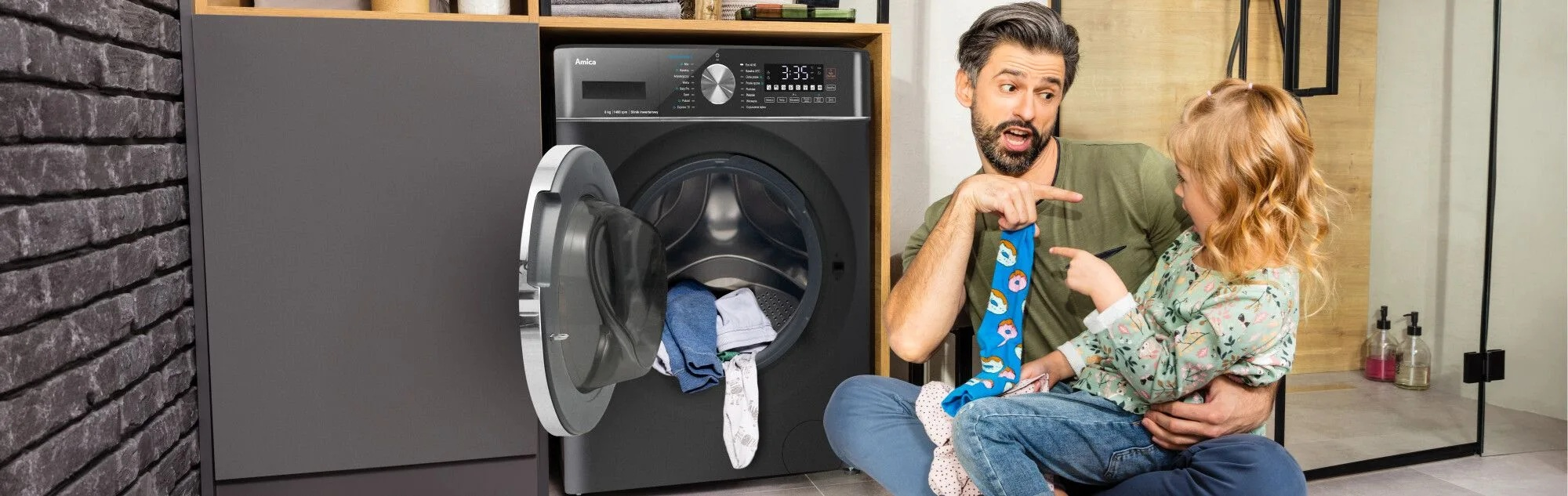 Mężczyzna i dziewczynka patrzą na skarpetkę. Pralka jest otwarta. W środku są ubrania.