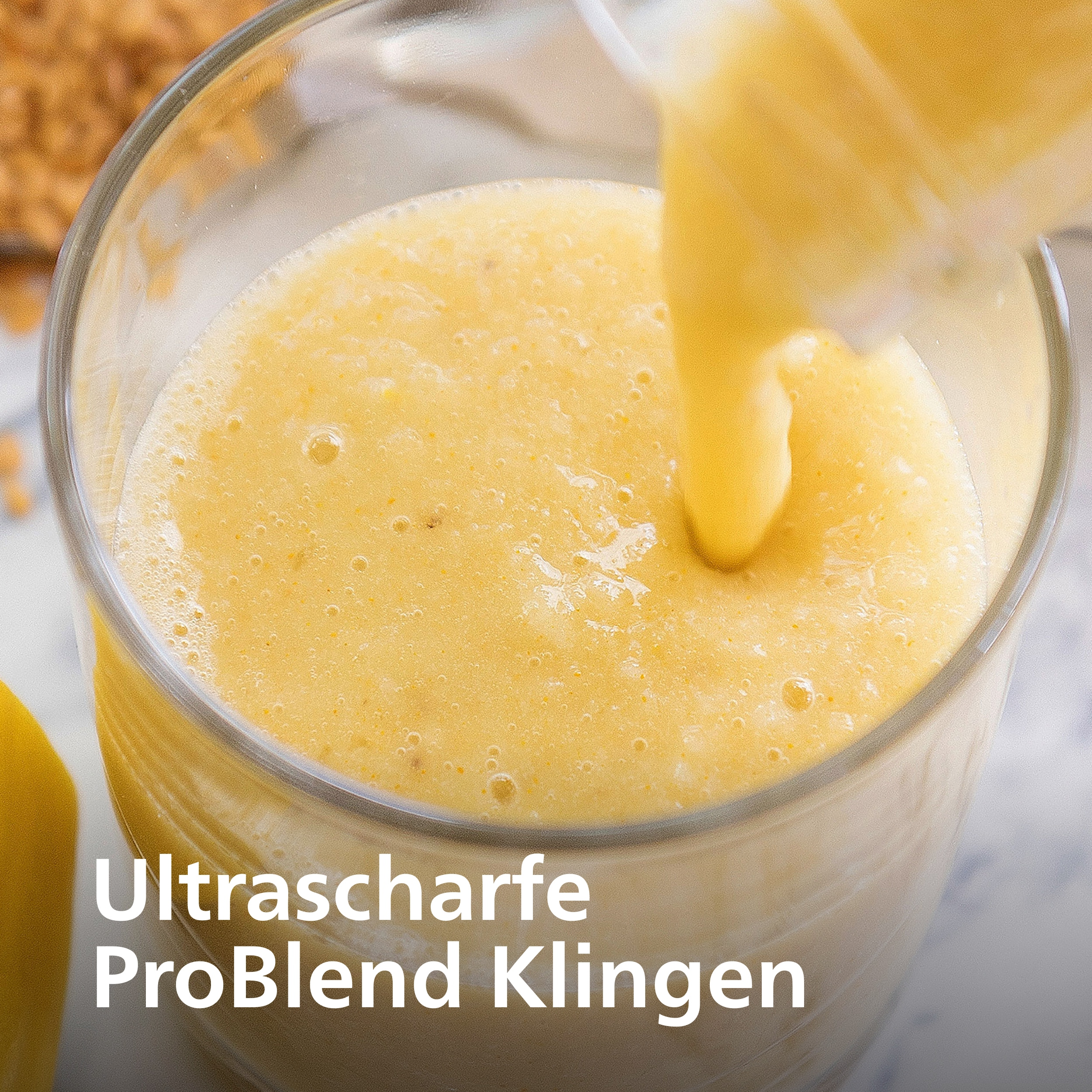 Ein Glas wird mit einem gelben Smoothie gefüllt. Das Getränk wird von oben in das Glas gegossen. Text ist sichtbar.