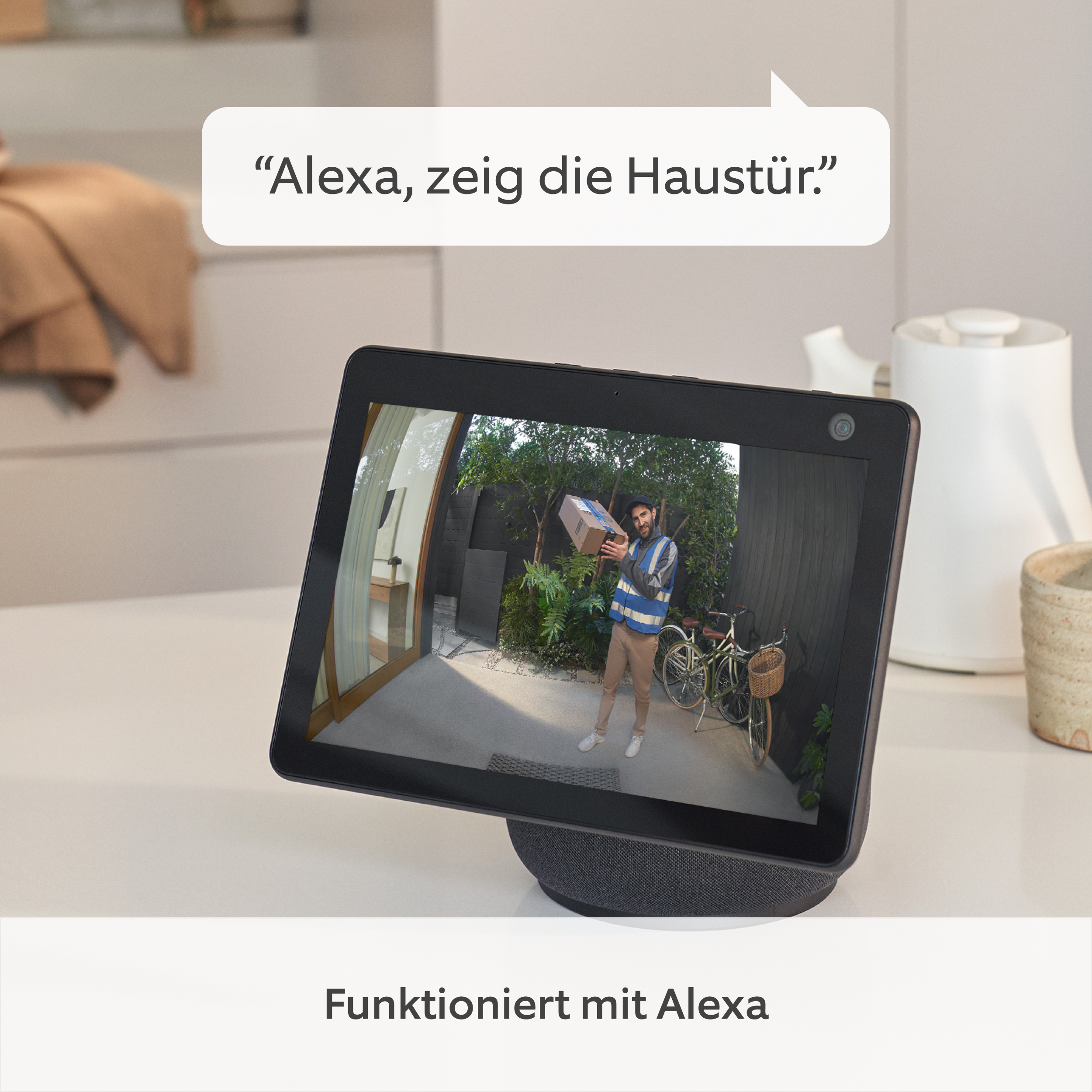 Tablet zeigt einen Zusteller. Sprechblase sagt 'Alexa, zeig die Haustür'. Funktioniert mit Alexa Text.