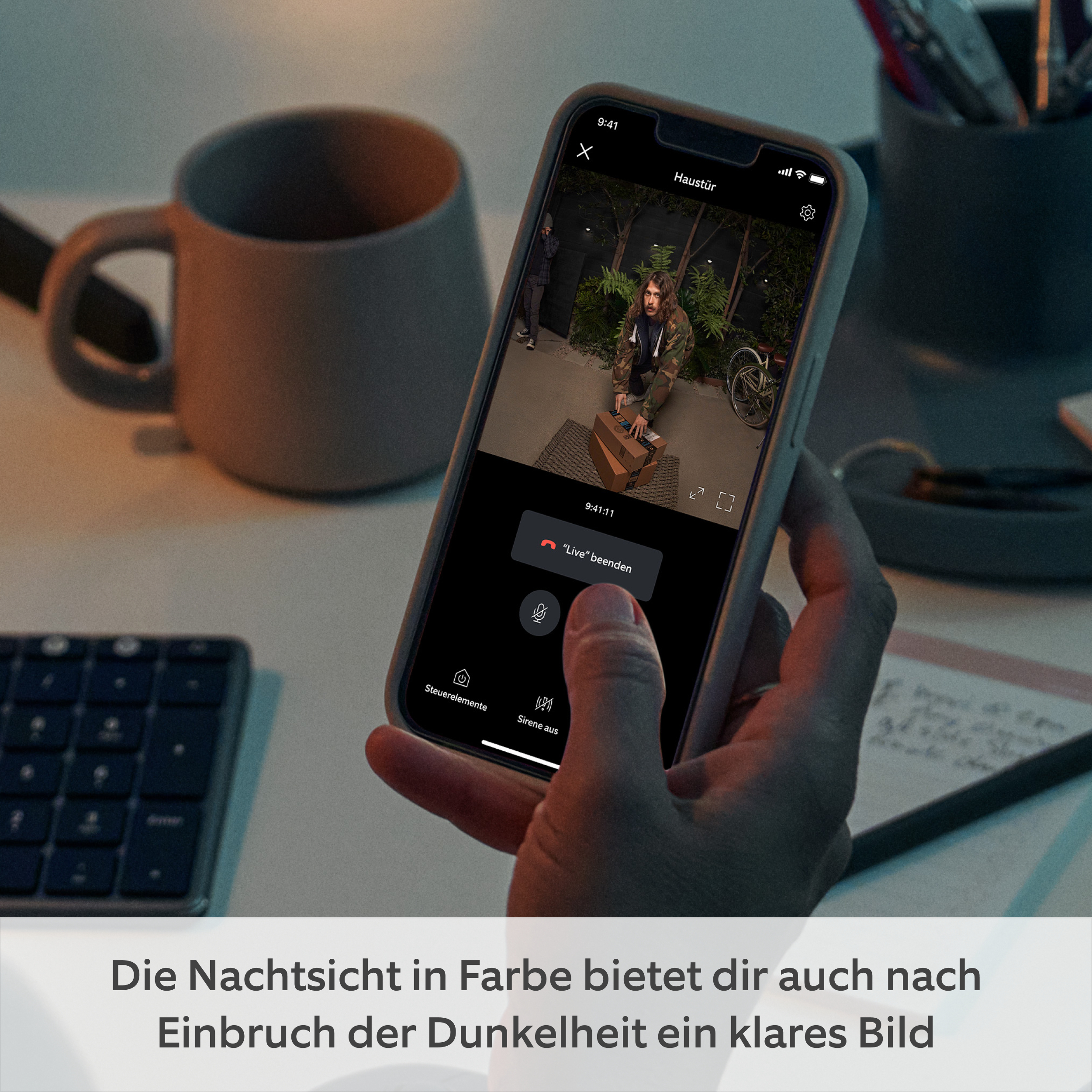 Ein Telefon zeigt ein Live-Video einer Person an einer Tür. Eine Hand hält das Telefon.